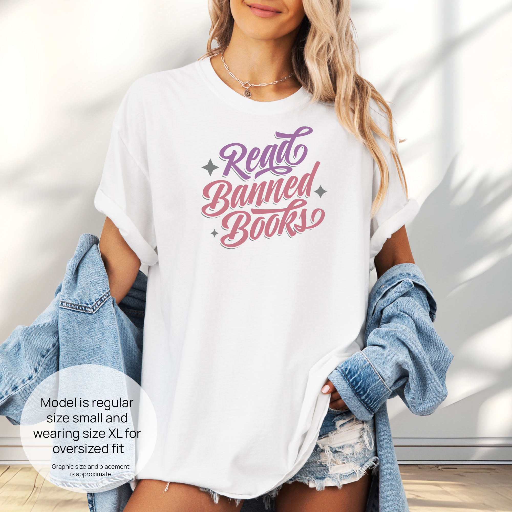 Female model wearing oversized white t-shirt with stylized text reading “Read Banned Books” in bold script lettering. Includes size and fit information for the model who is regular size small, and wearing a size XL shirt for an oversized fit.
