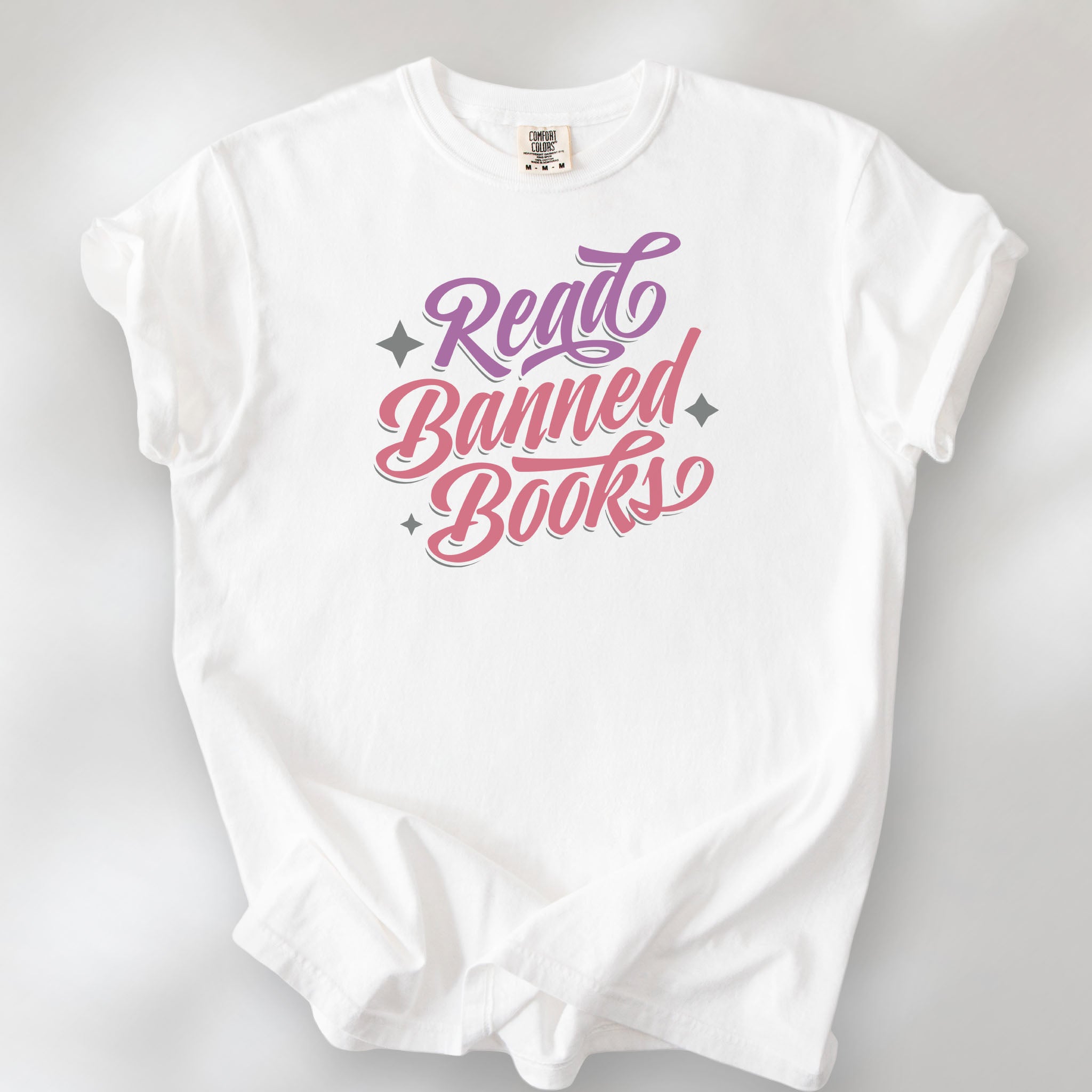 White t-shirt with stylized text reading “Read Banned Books” in bold script lettering.