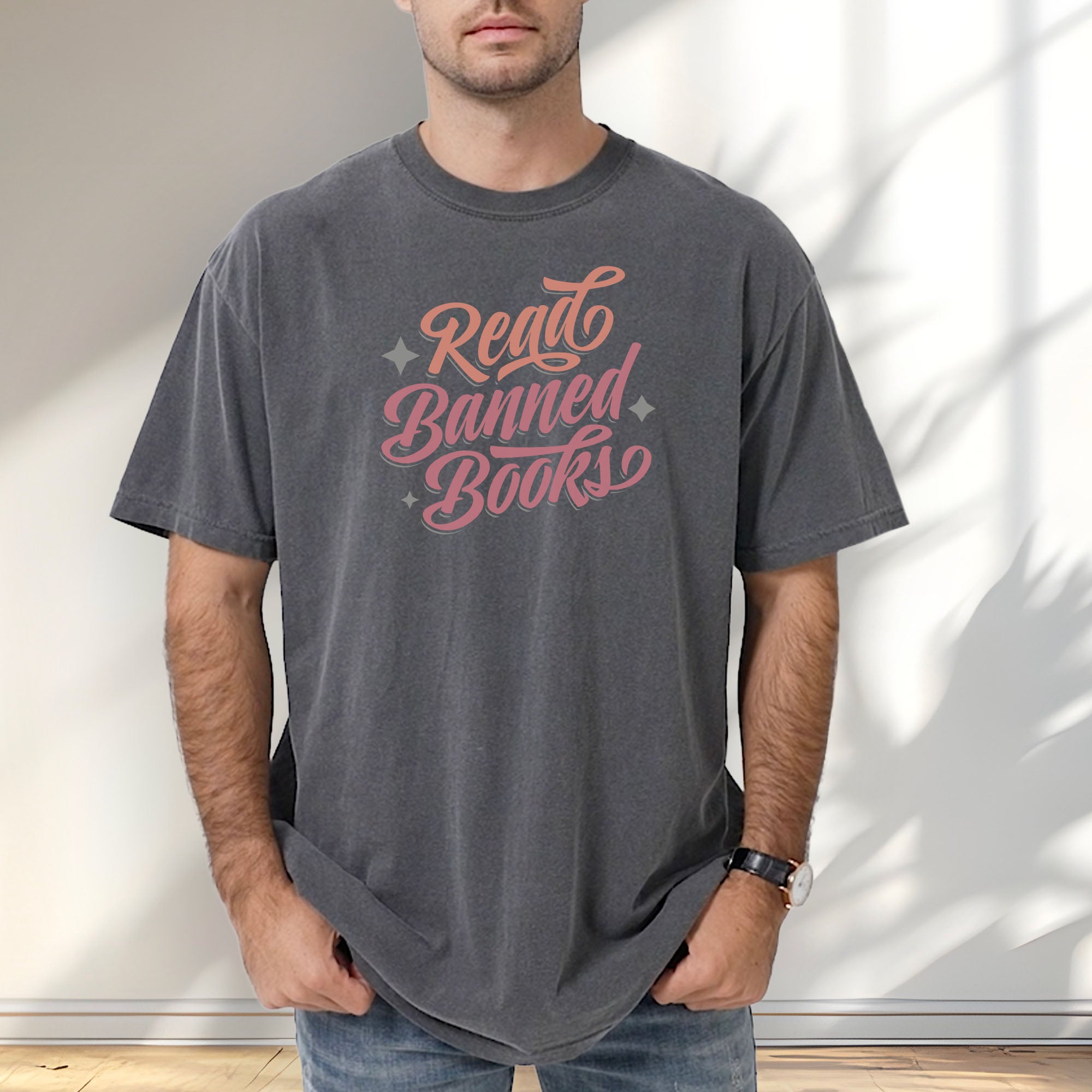 Male model wearing pepper t-shirt with stylized text reading “Read Banned Books” in bold script lettering.