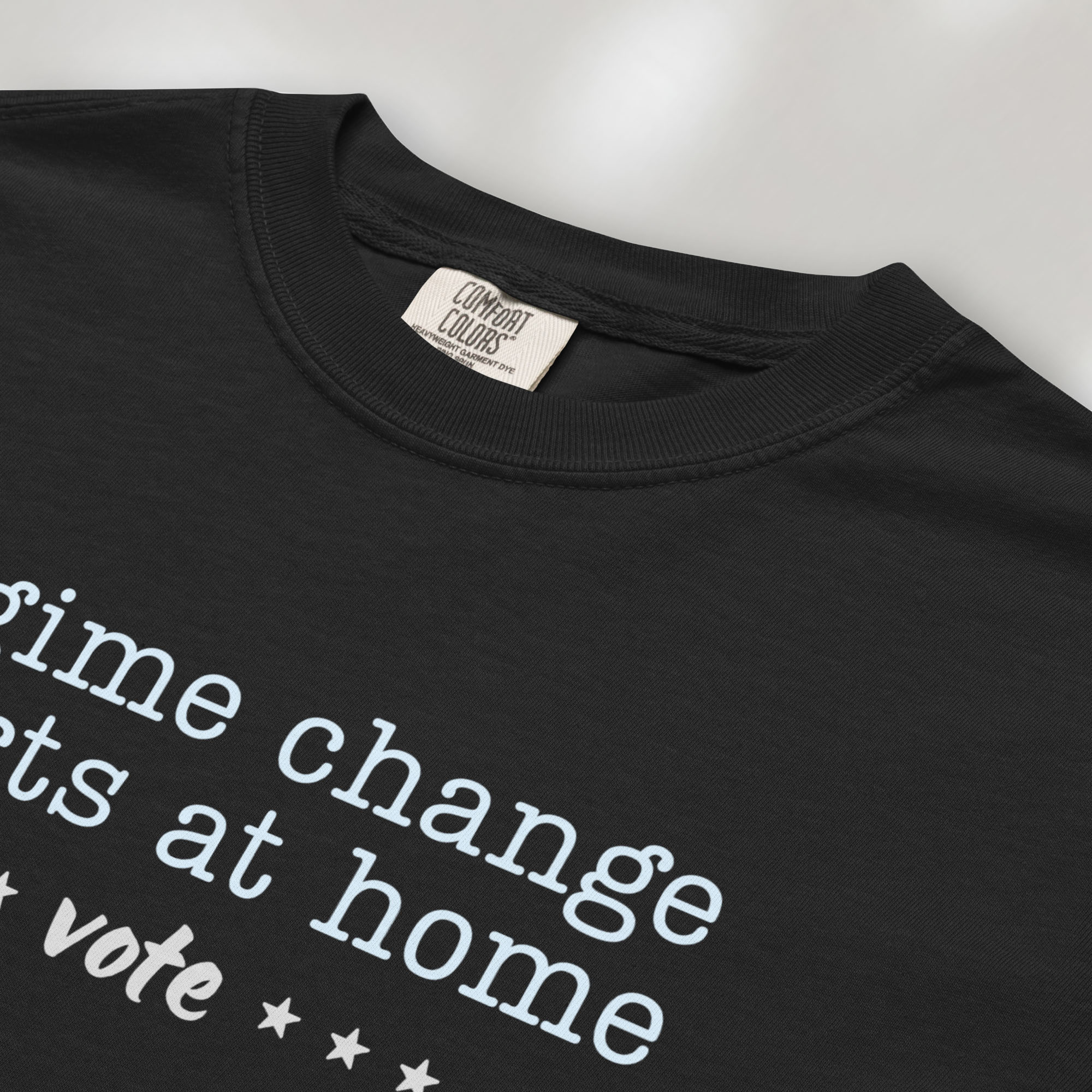 Closeup detail of black t-shirt with text that reads "regime change starts at home – vote."