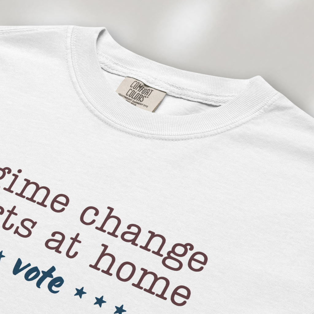 Closeup detail of white t-shirt with text that reads "regime change starts at home – vote."