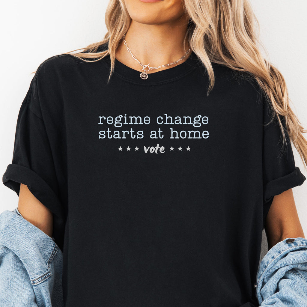 Female model wearing black t-shirt with text that reads "regime change starts at home – vote."