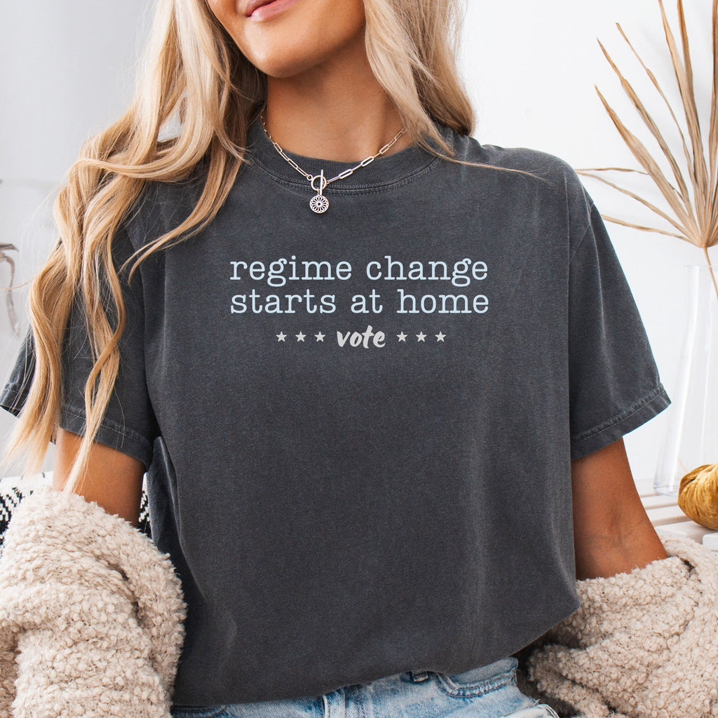 Female model wearing pepper t-shirt with text that reads "regime change starts at home – vote."