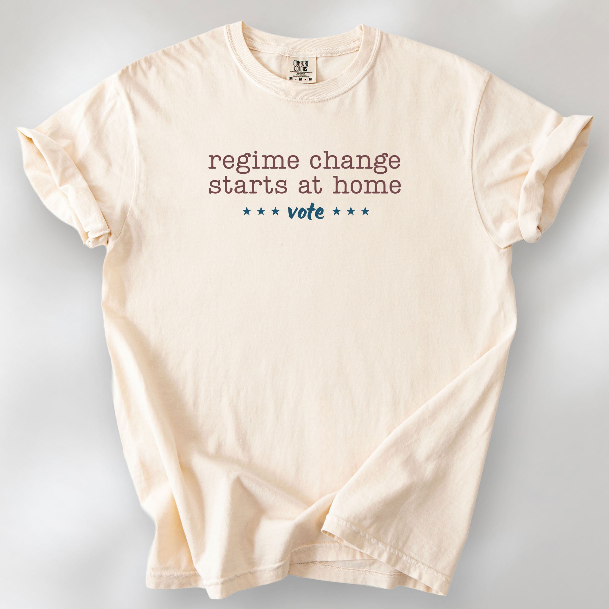 Ivory t-shirt with text that reads "regime change starts at home – vote."