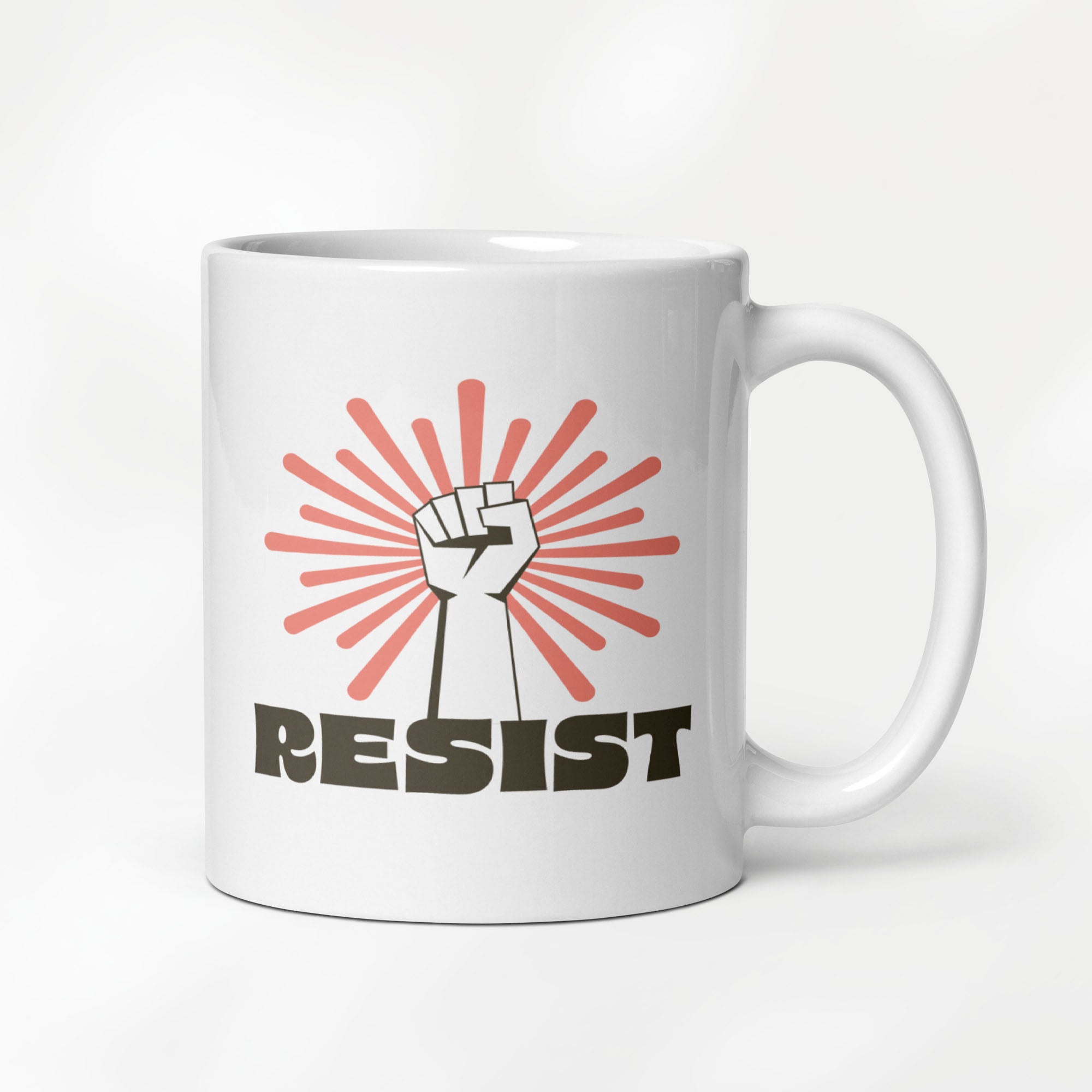 11 ounce ceramic mug with a raised fist graphic in front of a coral burst, and bold retro-styled text that says "resist."