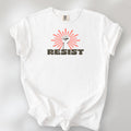 White t-shirt with retro style "resist" text, raised fist, and pinkish burst behind the fist.