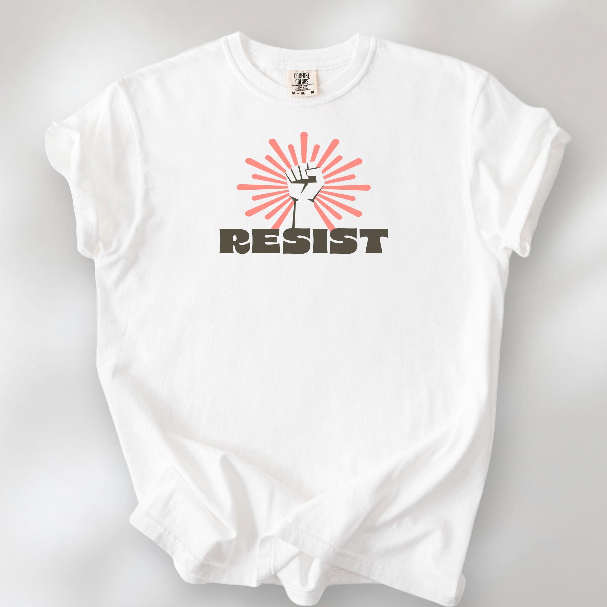 White t-shirt with retro style "resist" text, raised fist, and pinkish burst behind the fist.
