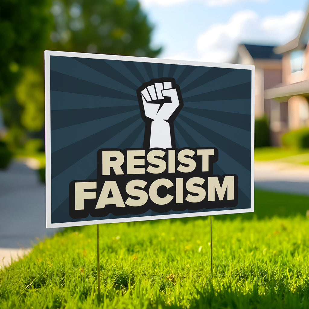 Yard sign with blue burst background and white raised fist above text that reads "Resist fascism" in all uppercase letters, planted in a green lawn.