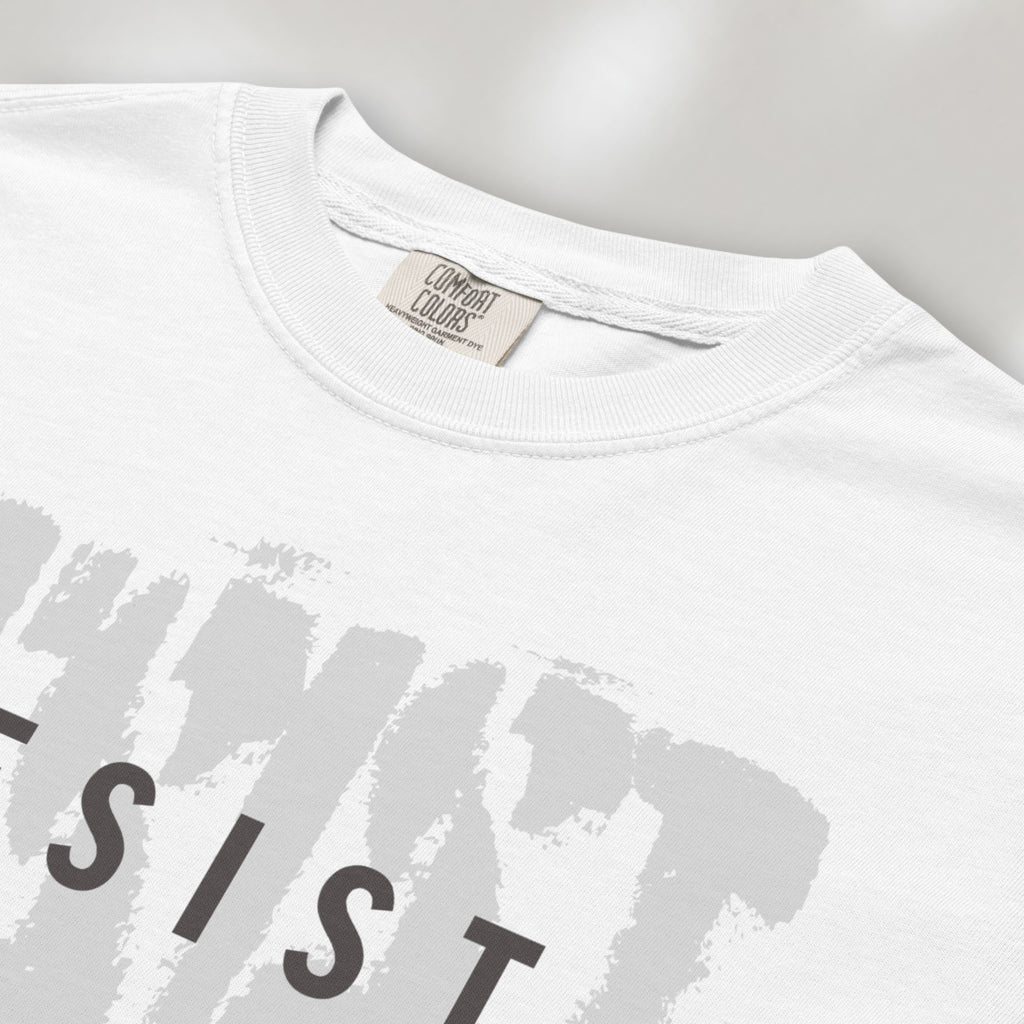 Closeup detail of white t-shirt with the word "resist" atop the word "resist" in a grunge background texture.