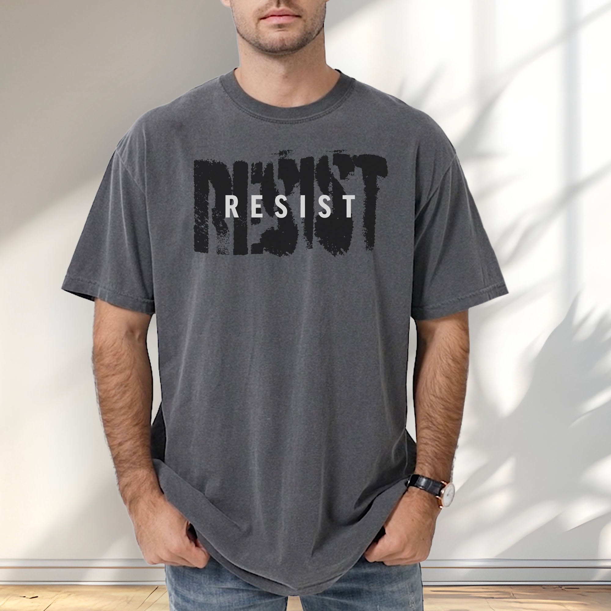 Male model wearing pepper t-shirt with the word "resist" atop the word "resist" in a grunge background texture.