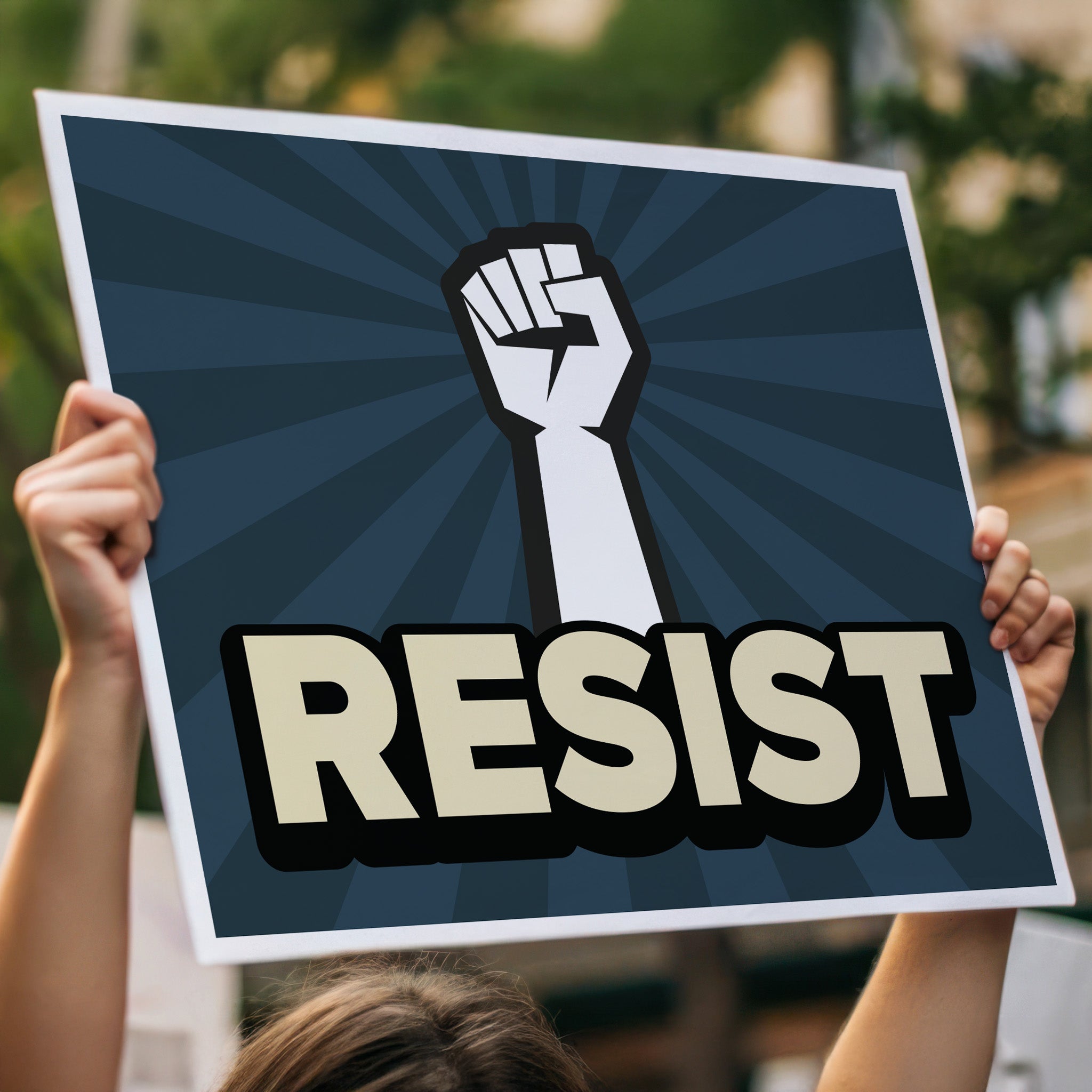 Anti-trump resistance protest sign with a raised fist and the word "Resist" below it, held high above a crowd.