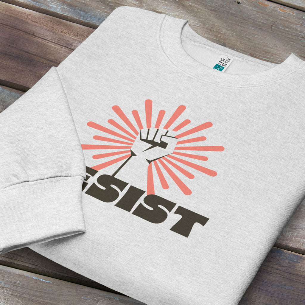 Folded grey sweatshirt with retro style "resist" text, raised fist, and pinkish burst behind the fist.