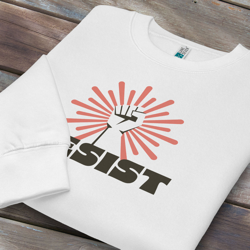 Folded white sweatshirt with retro style "resist" text, raised fist, and pinkish burst behind the fist.