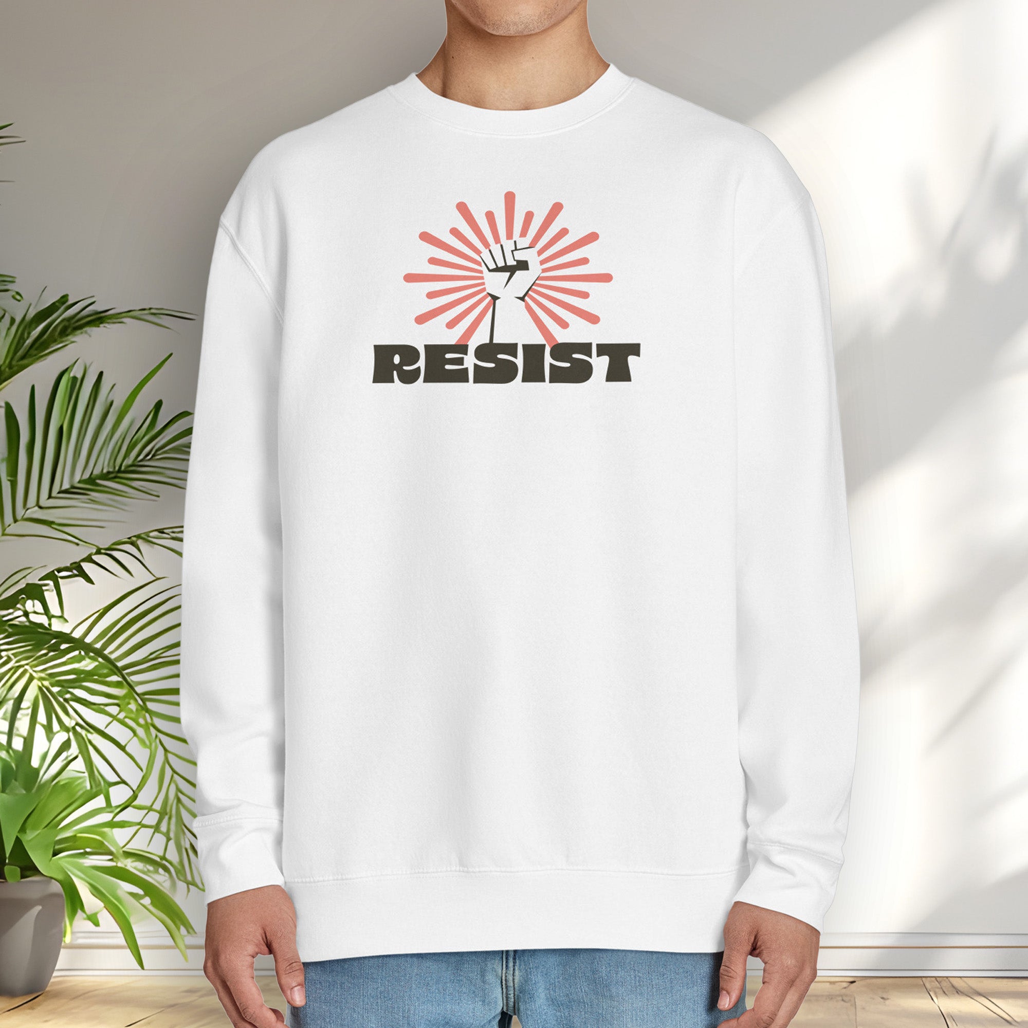 Male model wearing white sweatshirt with retro style "resist" text, raised fist, and pinkish burst behind the fist.