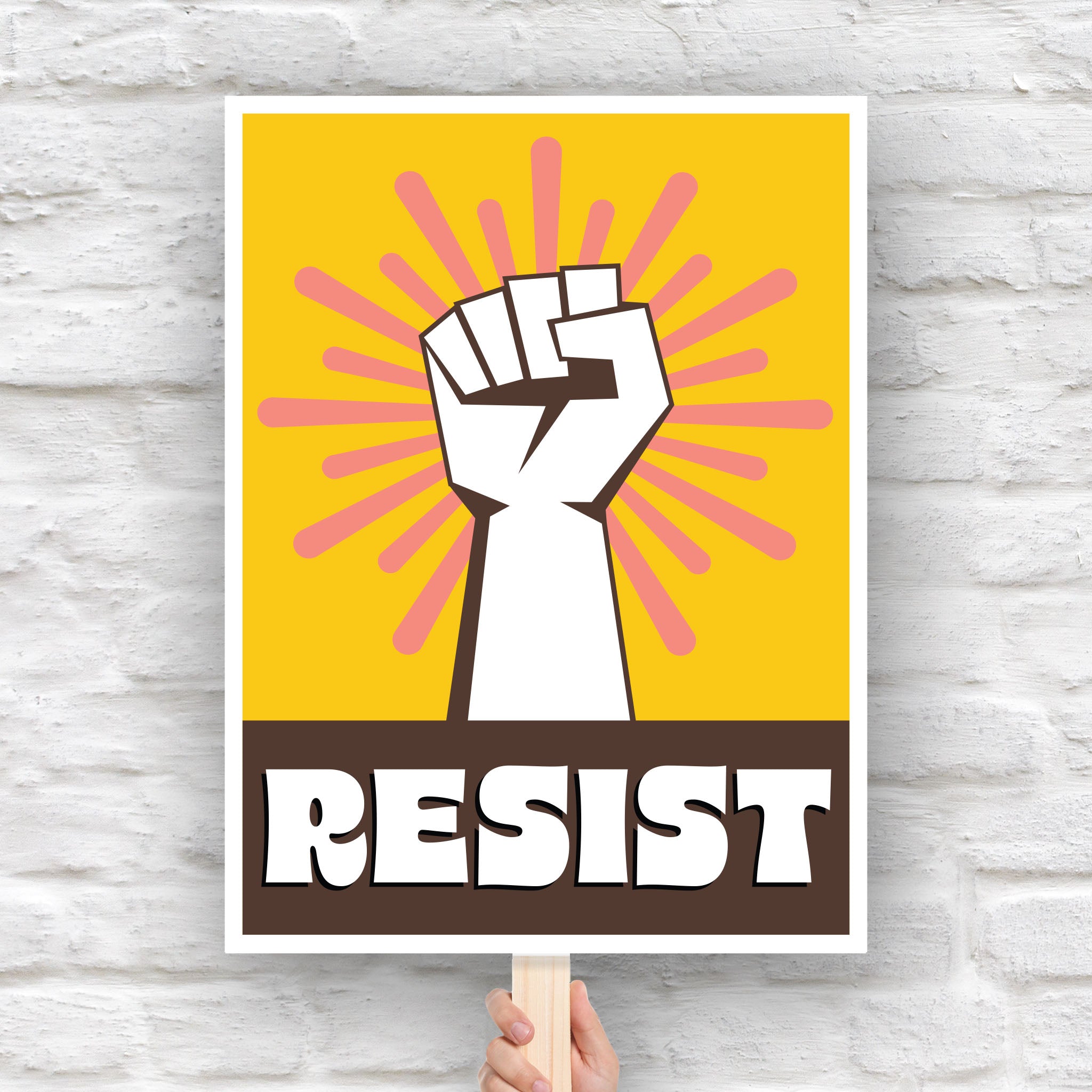 Downloadable, printable protest sign with yellow background behind a white raised fist and pink burst, with the retro-styled bold word "resist" below, reversed out of brown.
