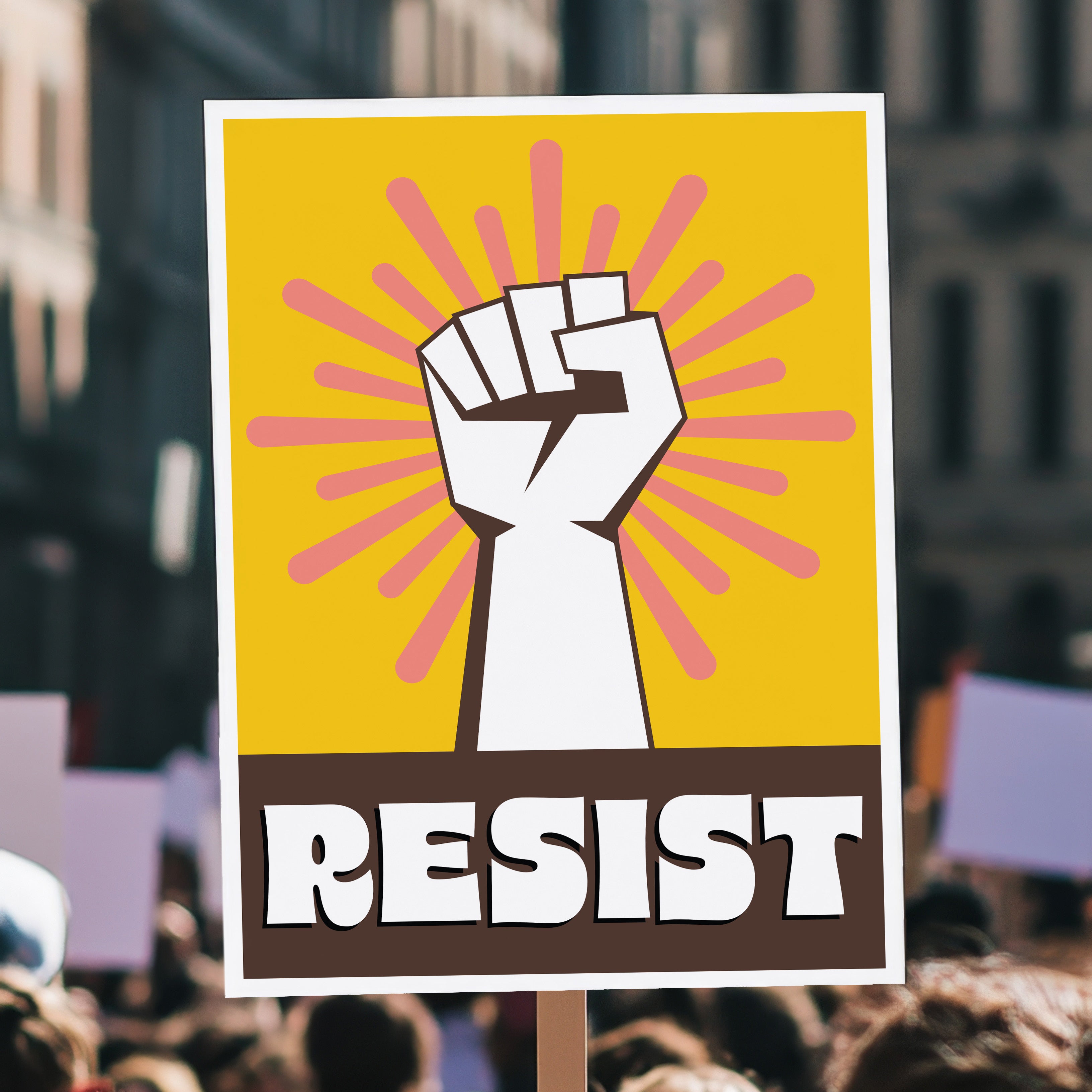 Protest sign with yellow background behind a white raised fist and pink burst, with the retro-styled bold word "resist" below, reversed out of brown, held high in a crowd.