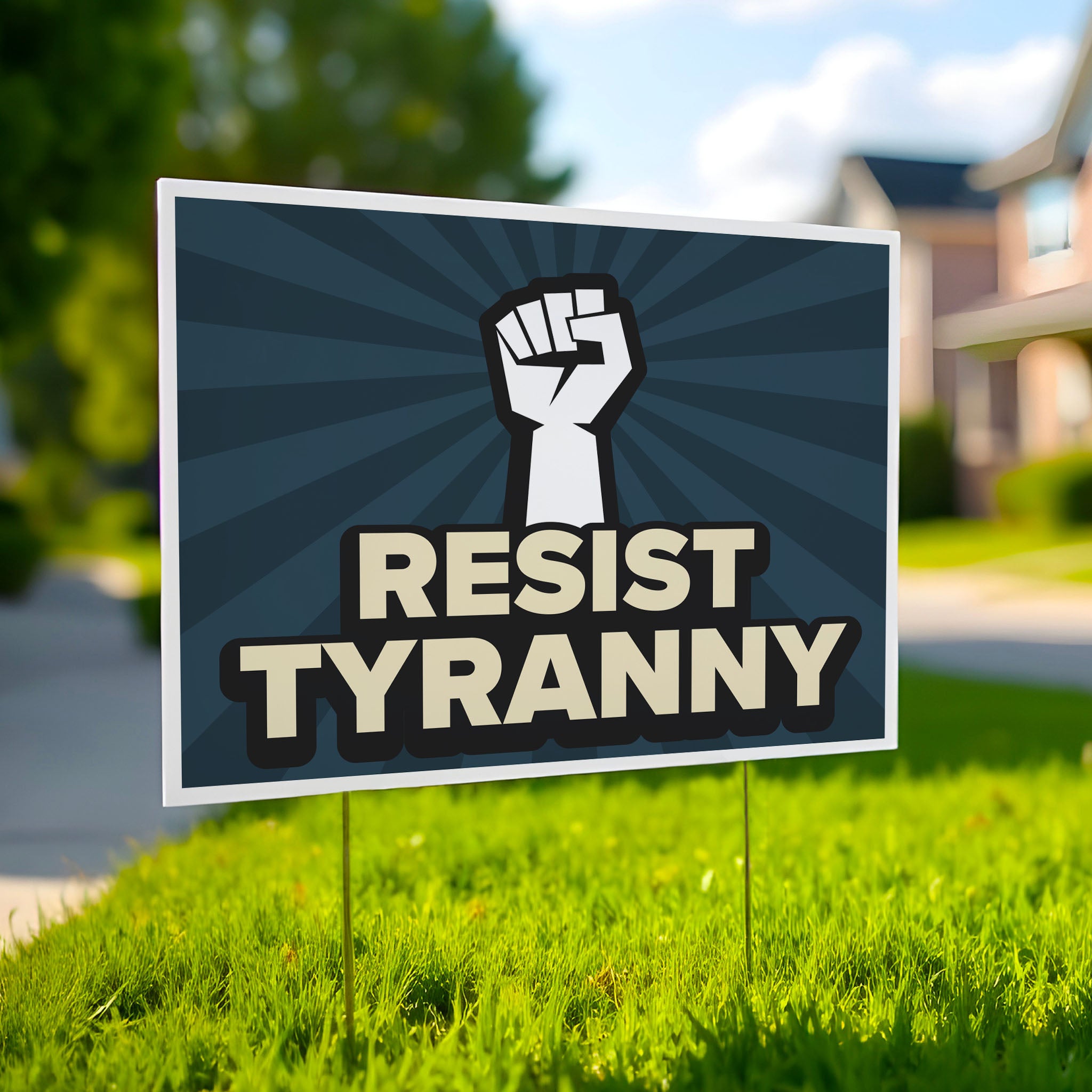 Yard sign with bold gold text on a blue background hat reads "resist tyranny" below a raised fist, planted in a green lawn.