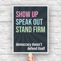 Downloadable, printable protest sign with dark background with subtle burst, bold colorful text that reads "show up, speak out, stand firm", then white bold text that reads "democracy doesn't defend itself."