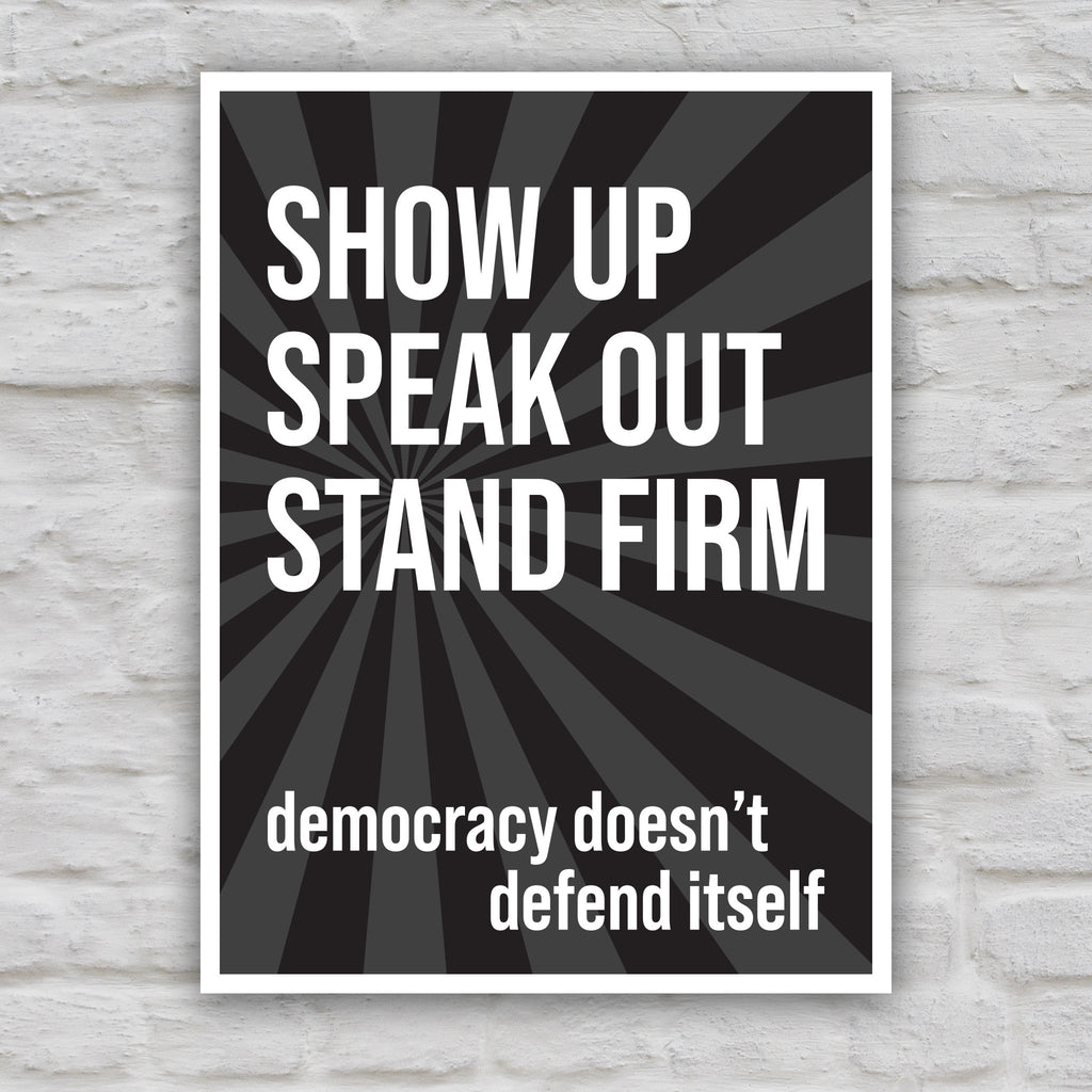 Black and white version of protest sign with dark background with subtle burst, bold white text that reads "show up, speak out, stand firm", then reads "democracy doesn't defend itself."