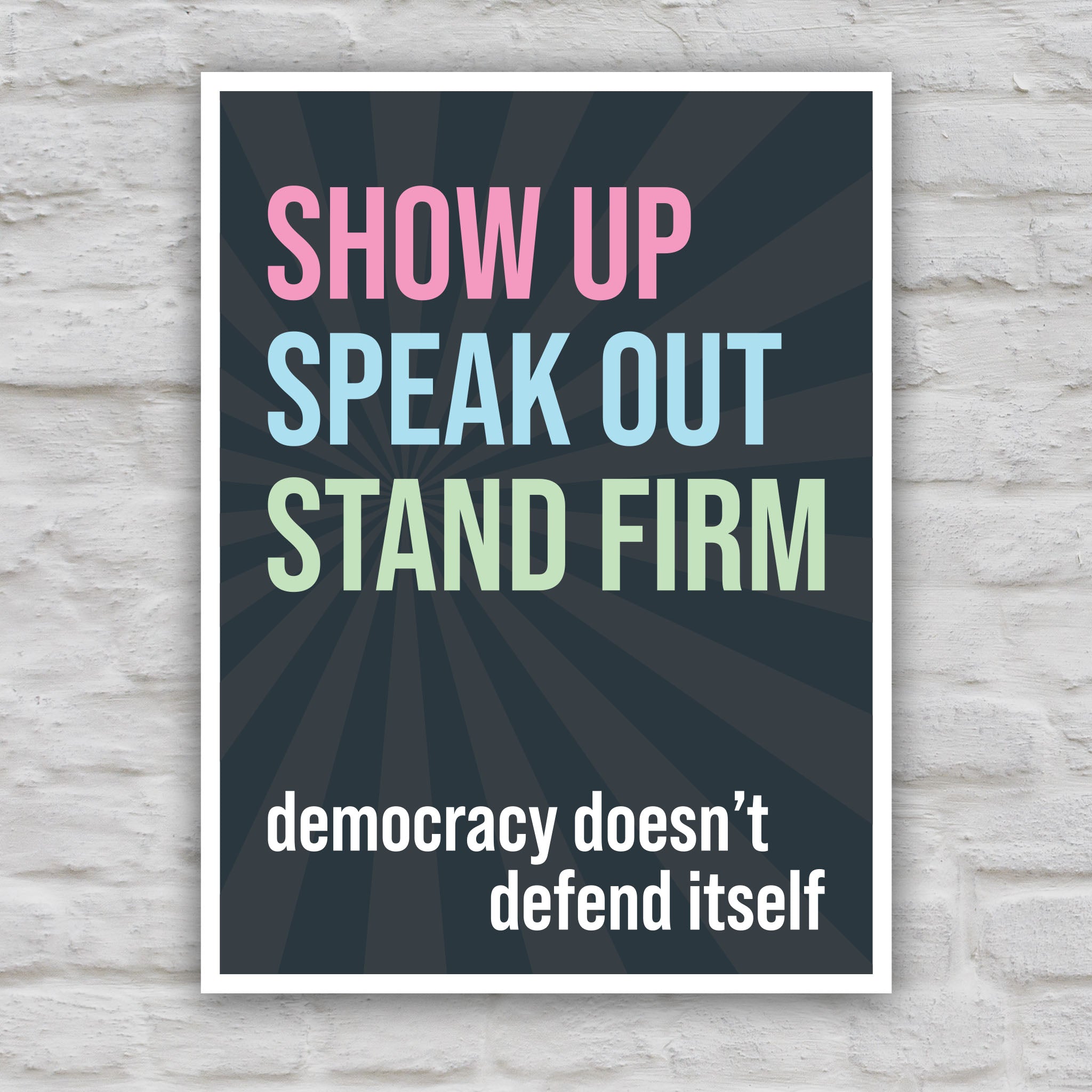 Color version of protest sign with dark background with subtle burst, bold colorful text that reads "show up, speak out, stand firm", then white bold text that reads "democracy doesn't defend itself."