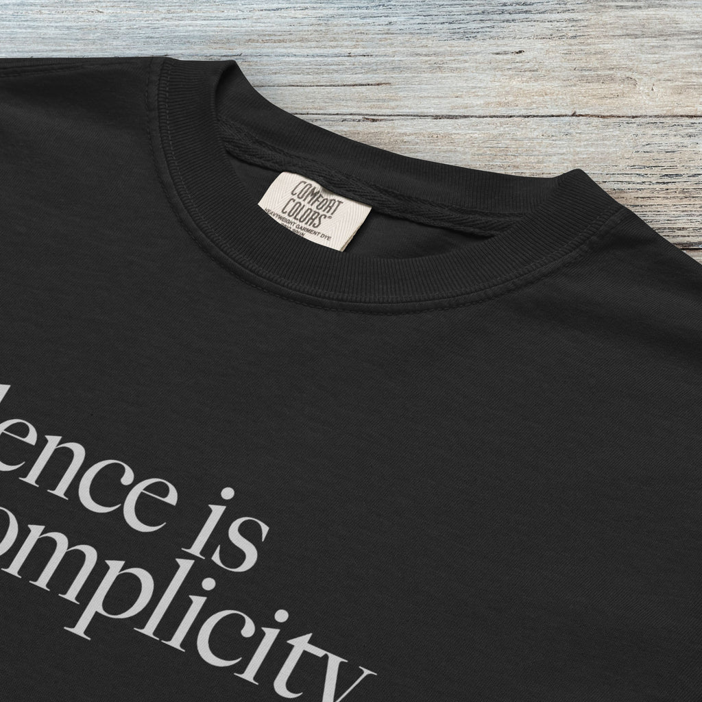 Closeup detail of black t-shirt with minimalist serif text reading “silence is complicity."