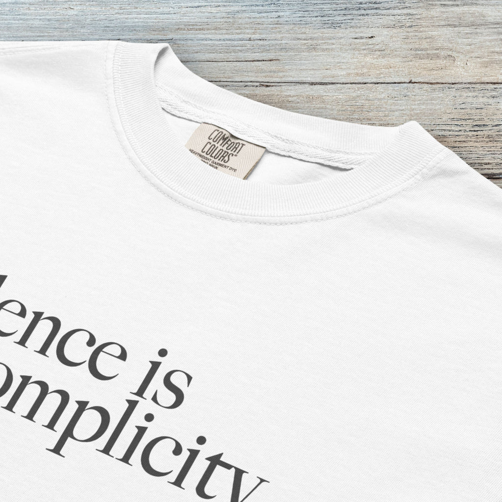 Closeup detail of white t-shirt with minimalist serif text reading “silence is complicity."
