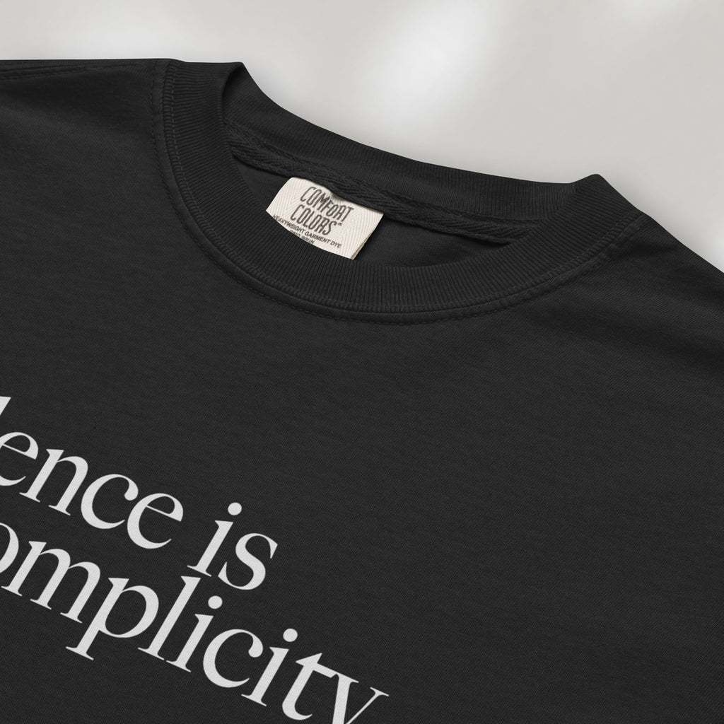 Closeup detail of black t-shirt with minimalist serif text reading “silence is complicity."
