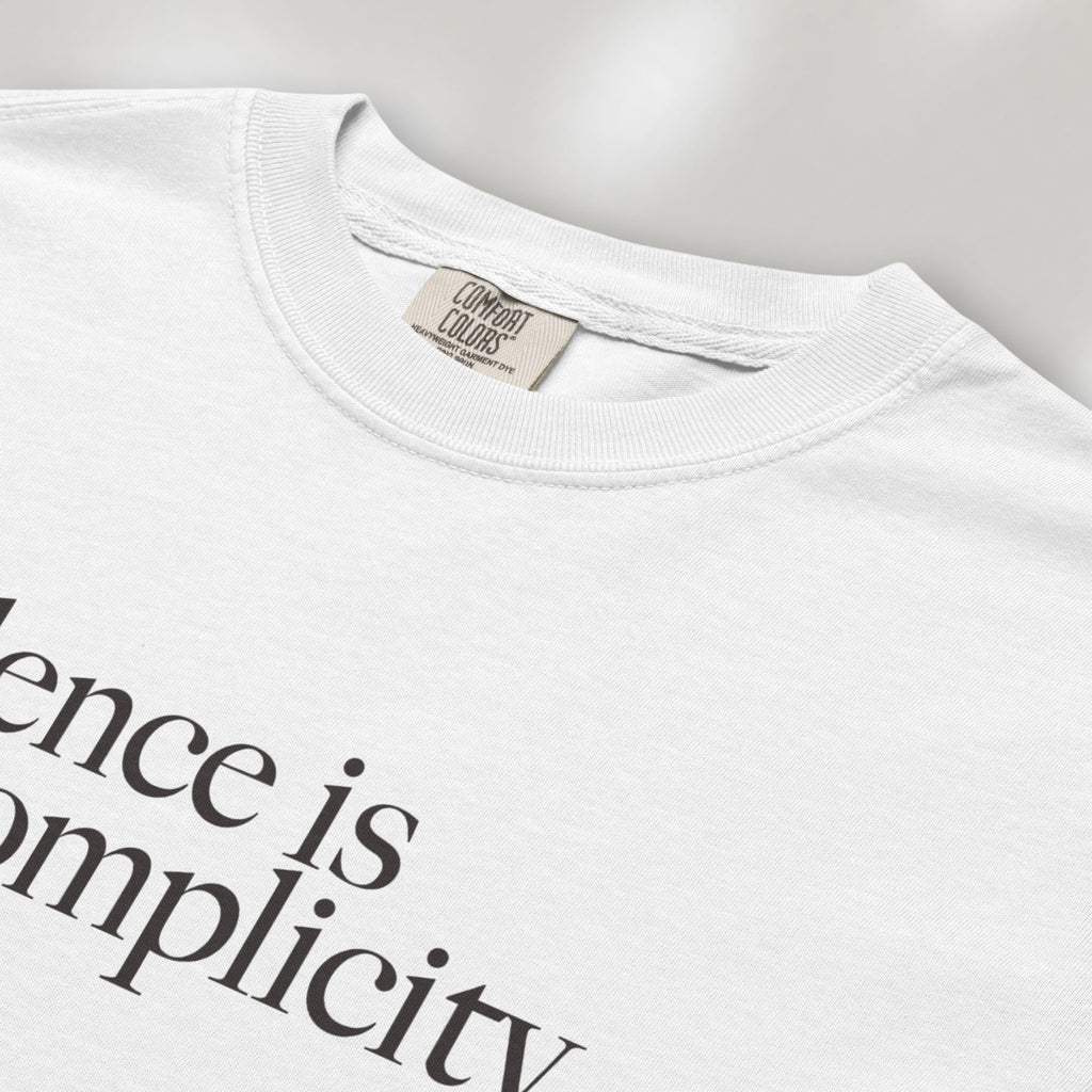 Closeup detail of white t-shirt with minimalist serif text reading “silence is complicity."