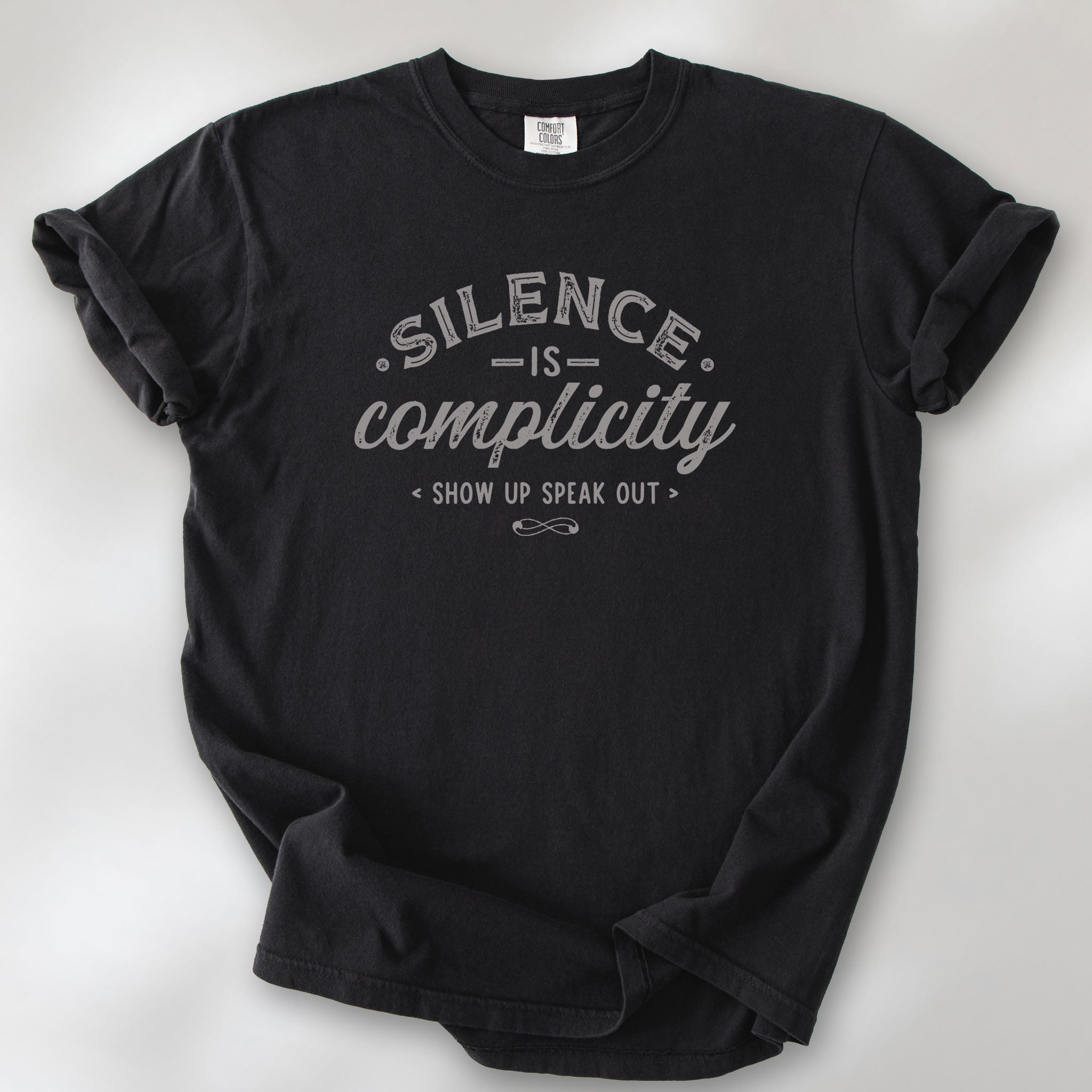 Black t-shirt with vintage distressed typography reading “Silence Is Complicity – Show Up Speak Out.”