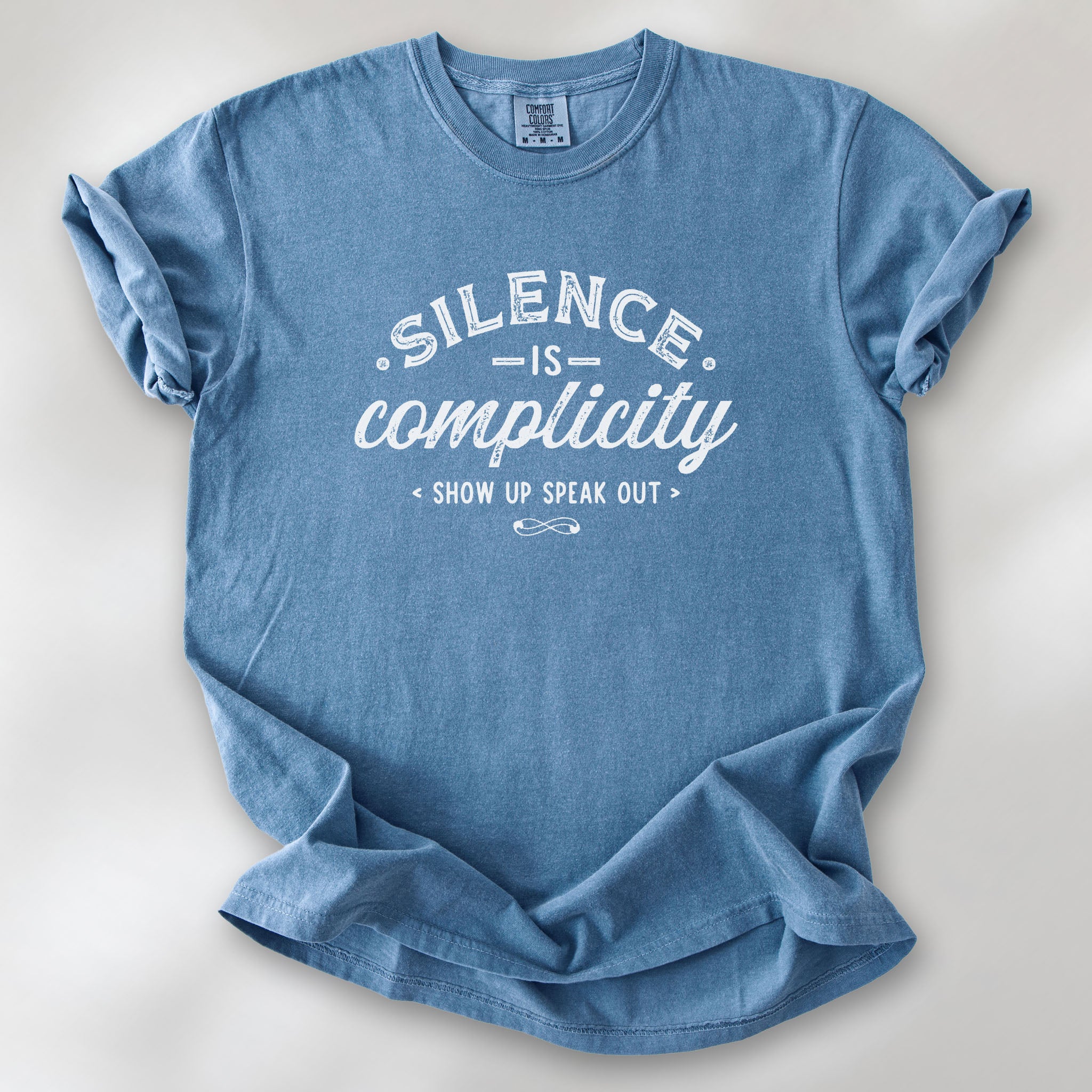 Blue jean t-shirt with vintage distressed typography reading “Silence Is Complicity – Show Up Speak Out.”