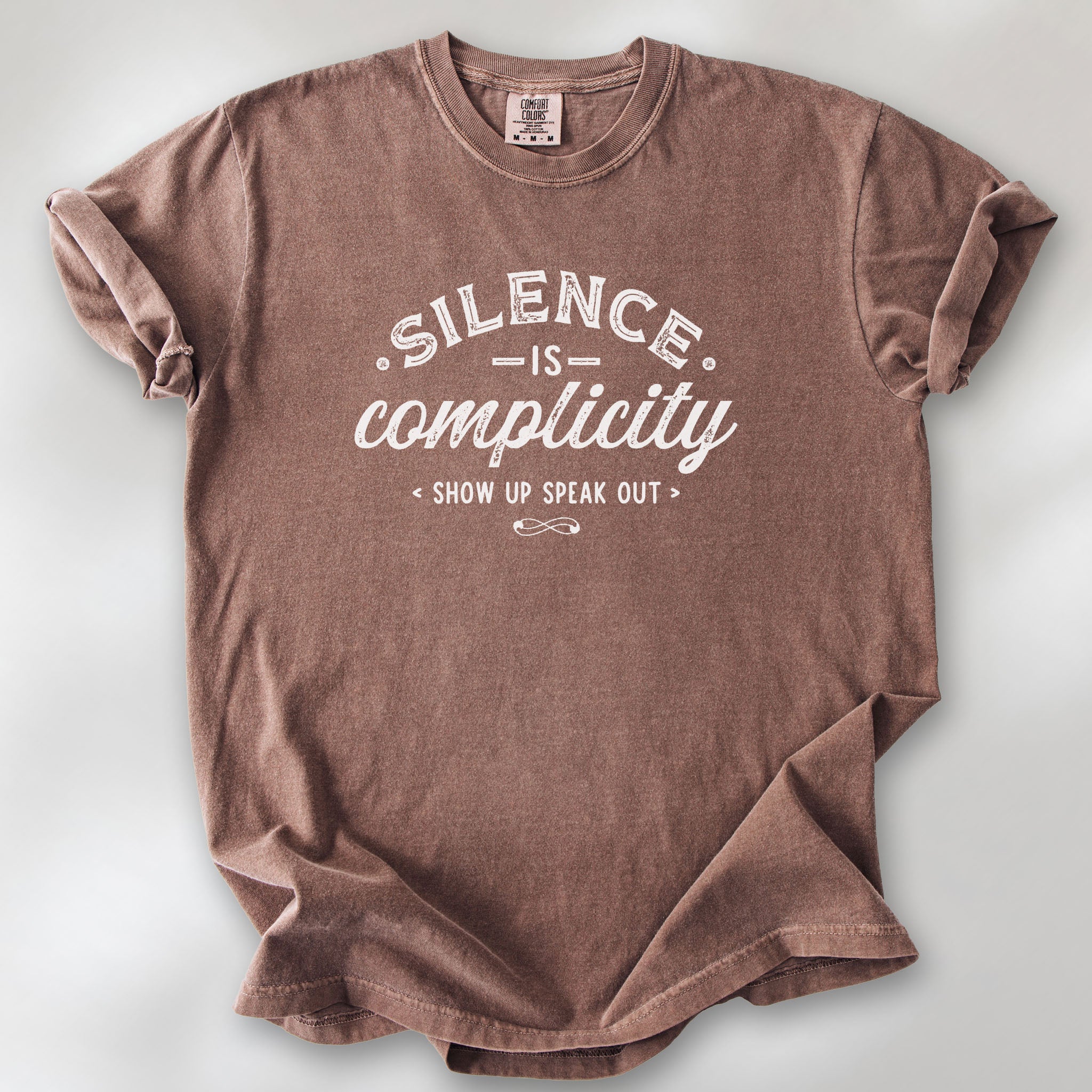 Espresso t-shirt with vintage distressed typography reading “Silence Is Complicity – Show Up Speak Out.”