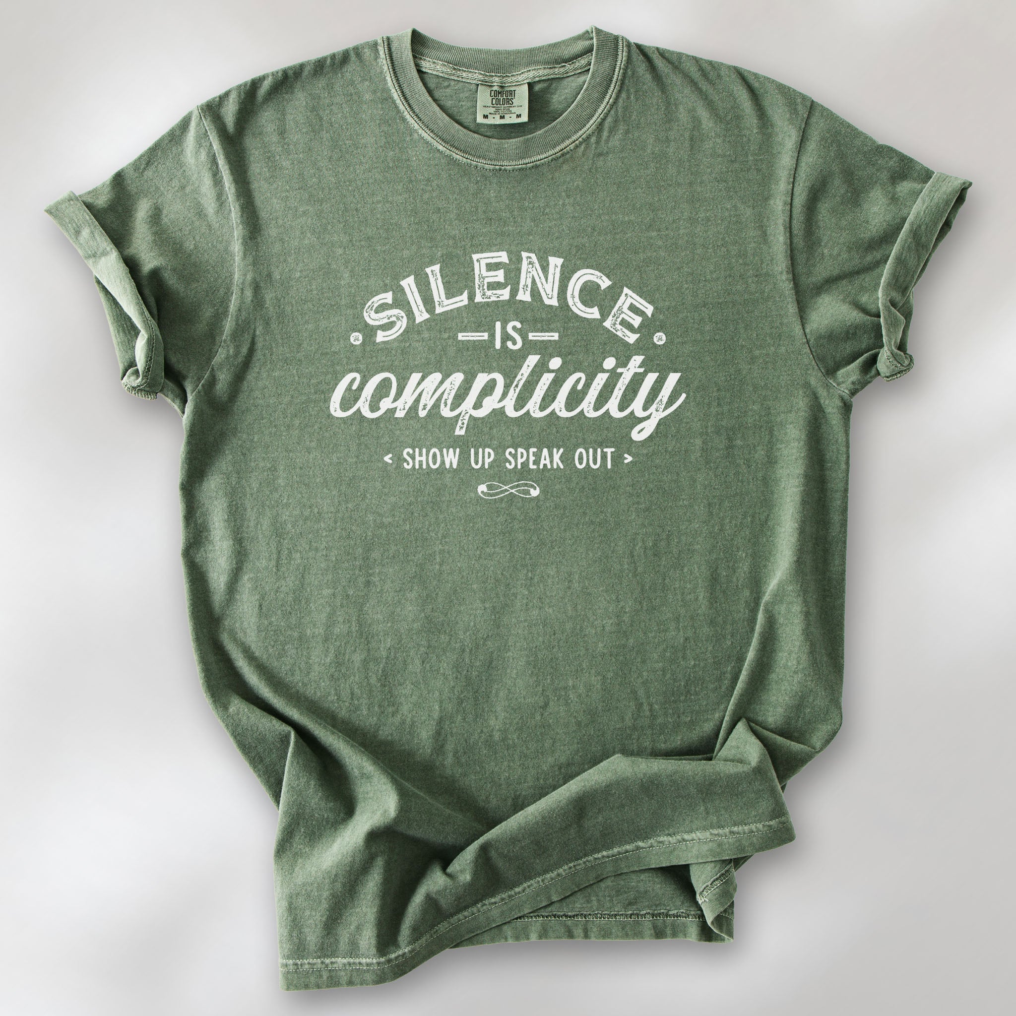 Moss t-shirt with vintage distressed typography reading “Silence Is Complicity – Show Up Speak Out.”