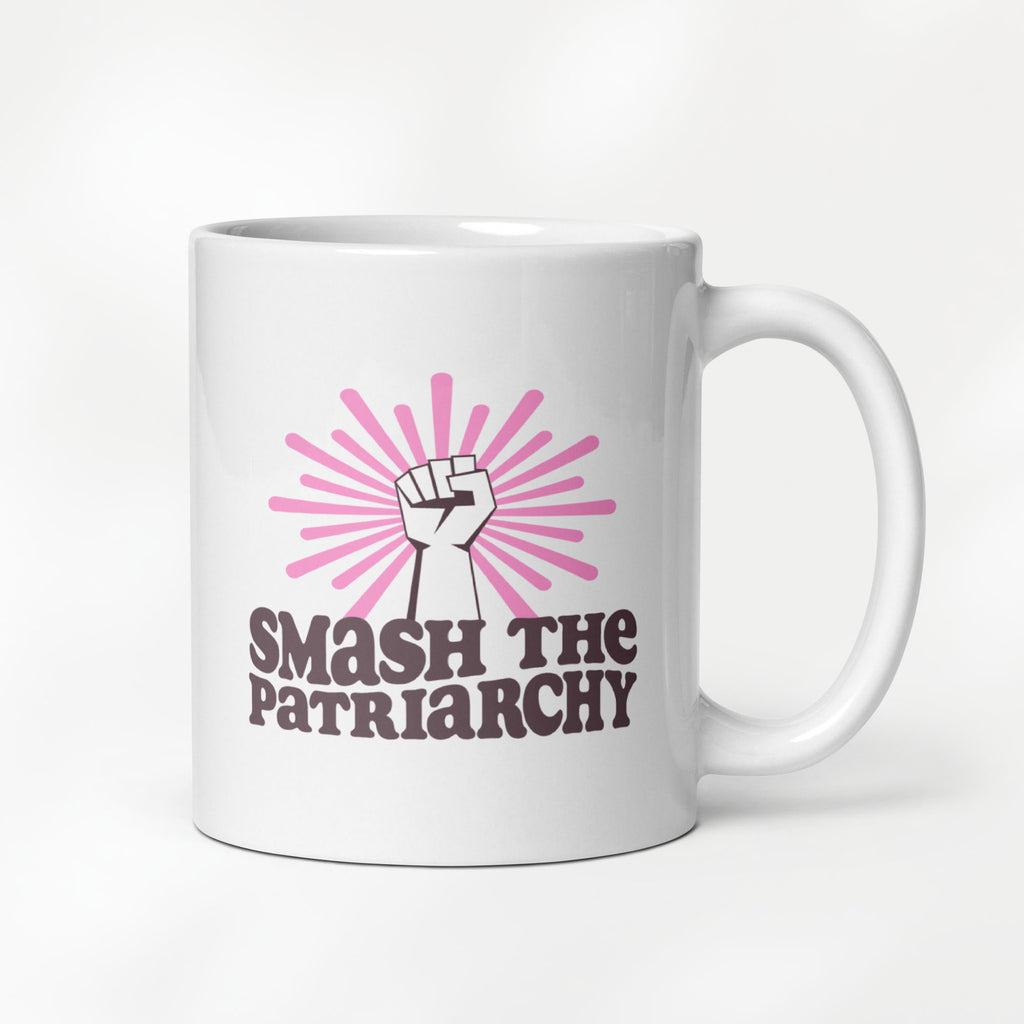 11 ounce ceramic mug that says "smash the patriarchy" below a raised fist centered in front of pink rays.