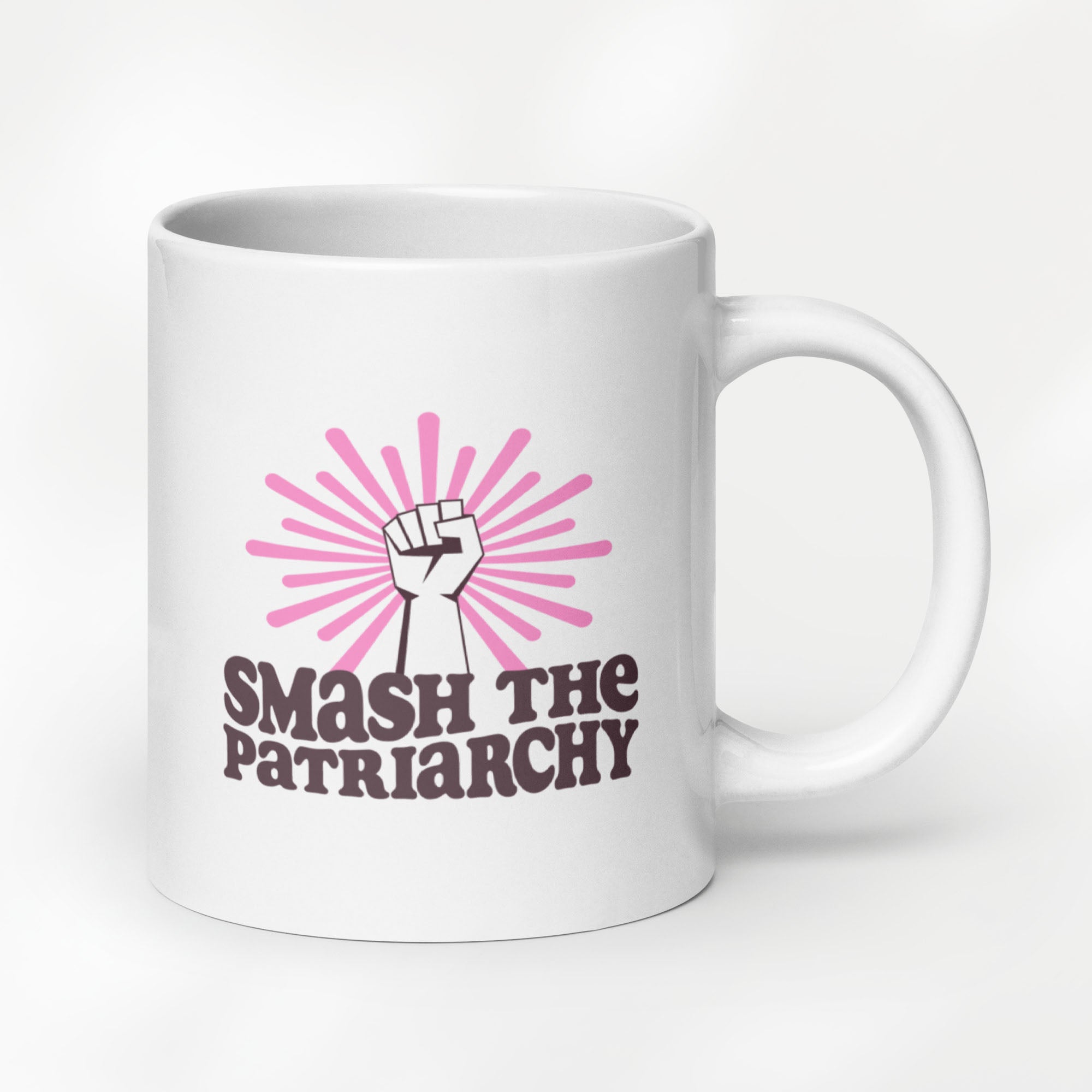 20 ounce ceramic mug that says "smash the patriarchy" below a raised fist centered in front of pink rays.