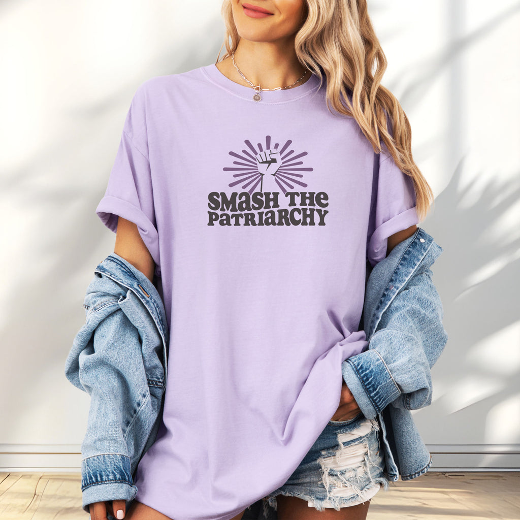 Female model wearing oversized orchid t-shirt with a raised fist graphic and purple burst above the text “Smash the Patriarchy.”