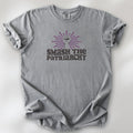 Grey t-shirt with a raised fist graphic and purple burst above the text “Smash the Patriarchy.”
