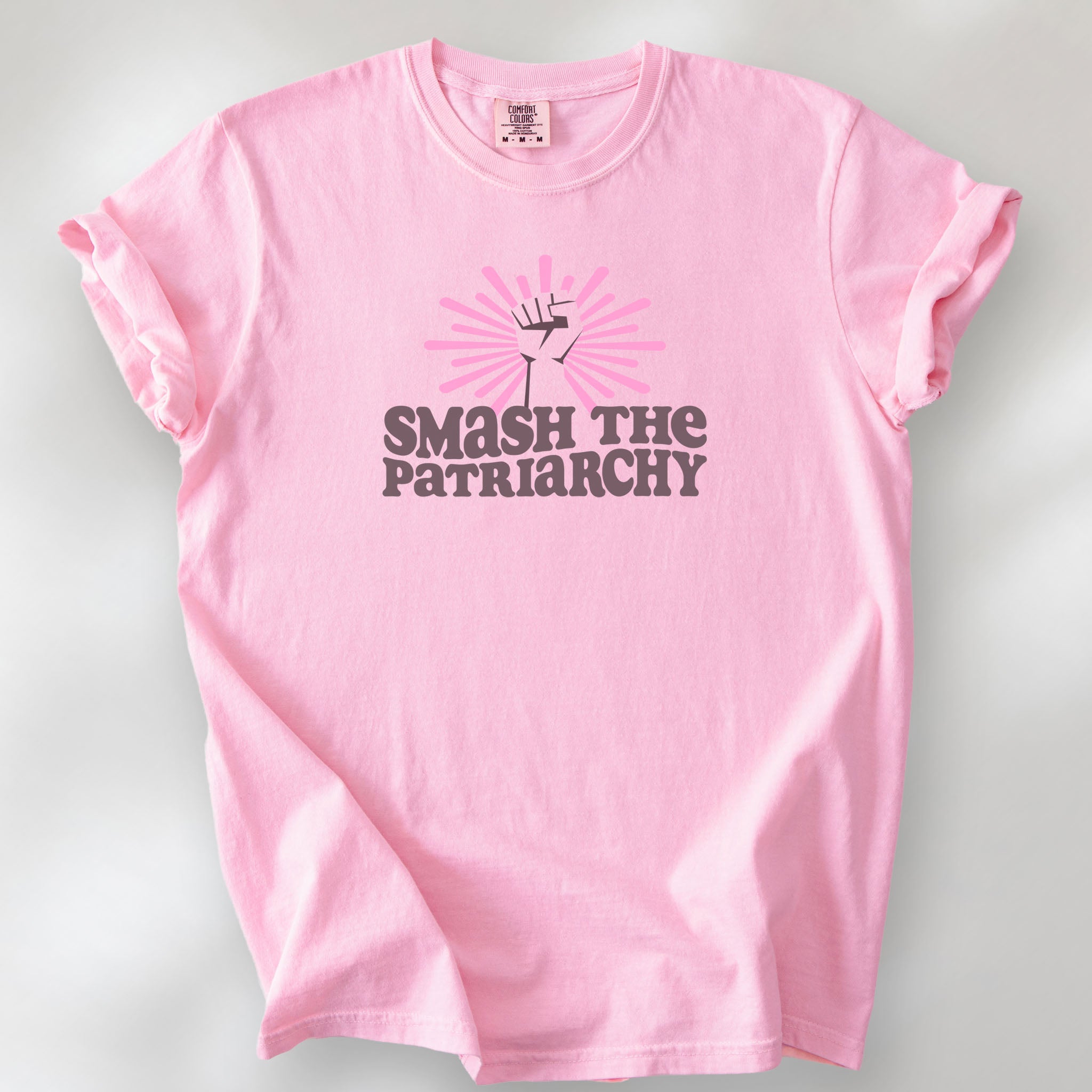 Blossom t-shirt with a raised fist graphic and pink rays behind it, featuring the text “Smash the Patriarchy.”