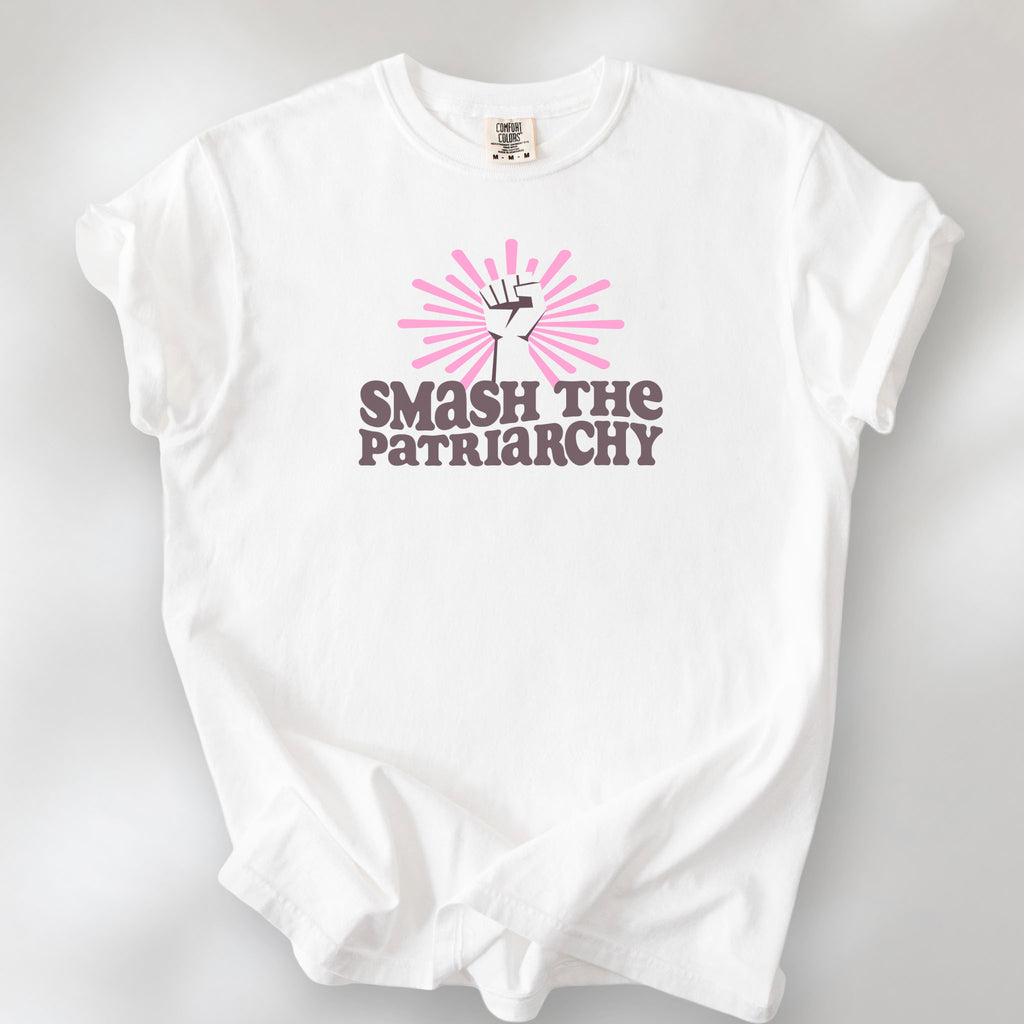 White t-shirt with a raised fist graphic and pink rays behind it, featuring the text “Smash the Patriarchy.”