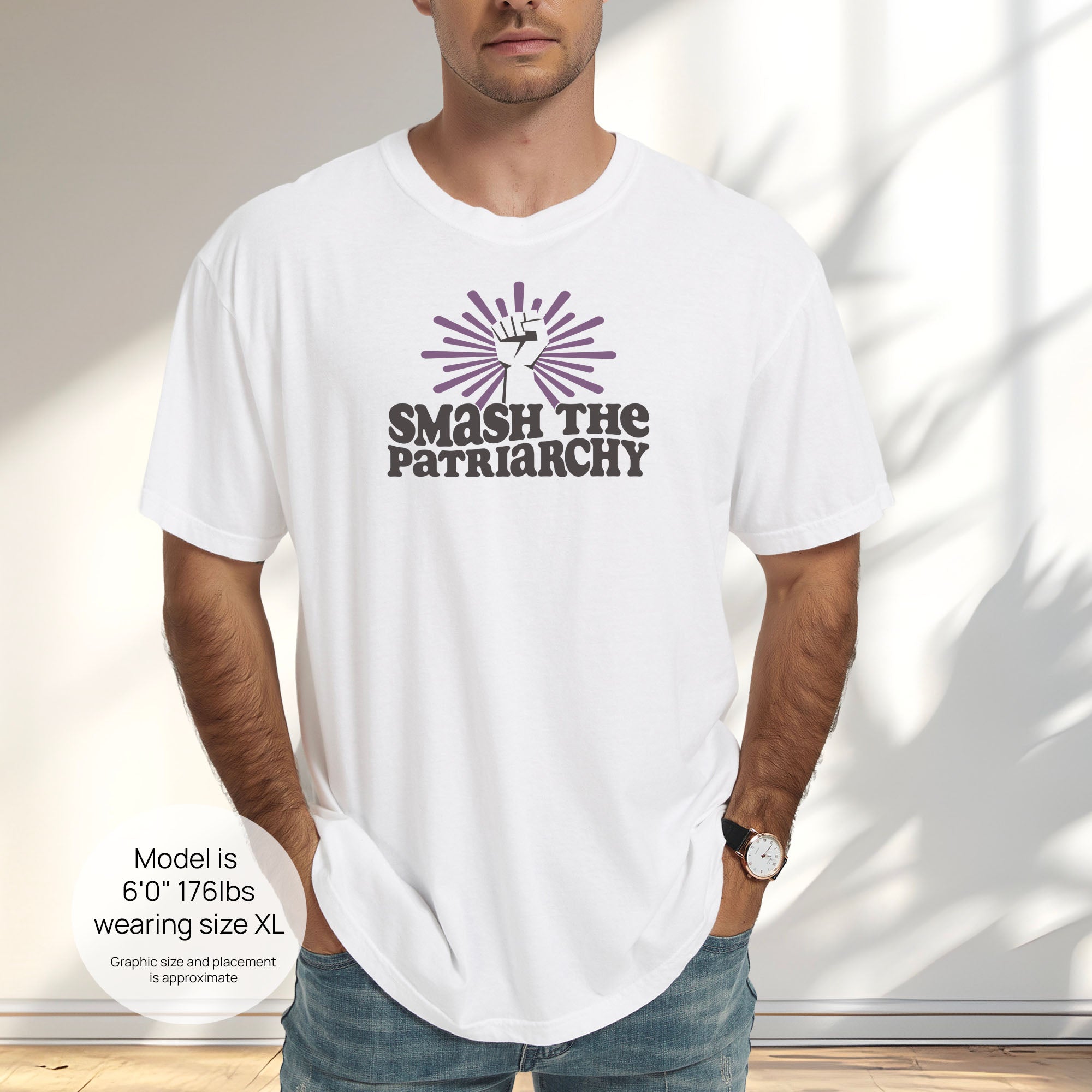 Male model wearing white t-shirt with a raised fist graphic and purple burst above the text “Smash the Patriarchy.” Includes size and fit information for the model who is 6 feet 0 inches, 176 pounds, and wearing a size XL shirt.
