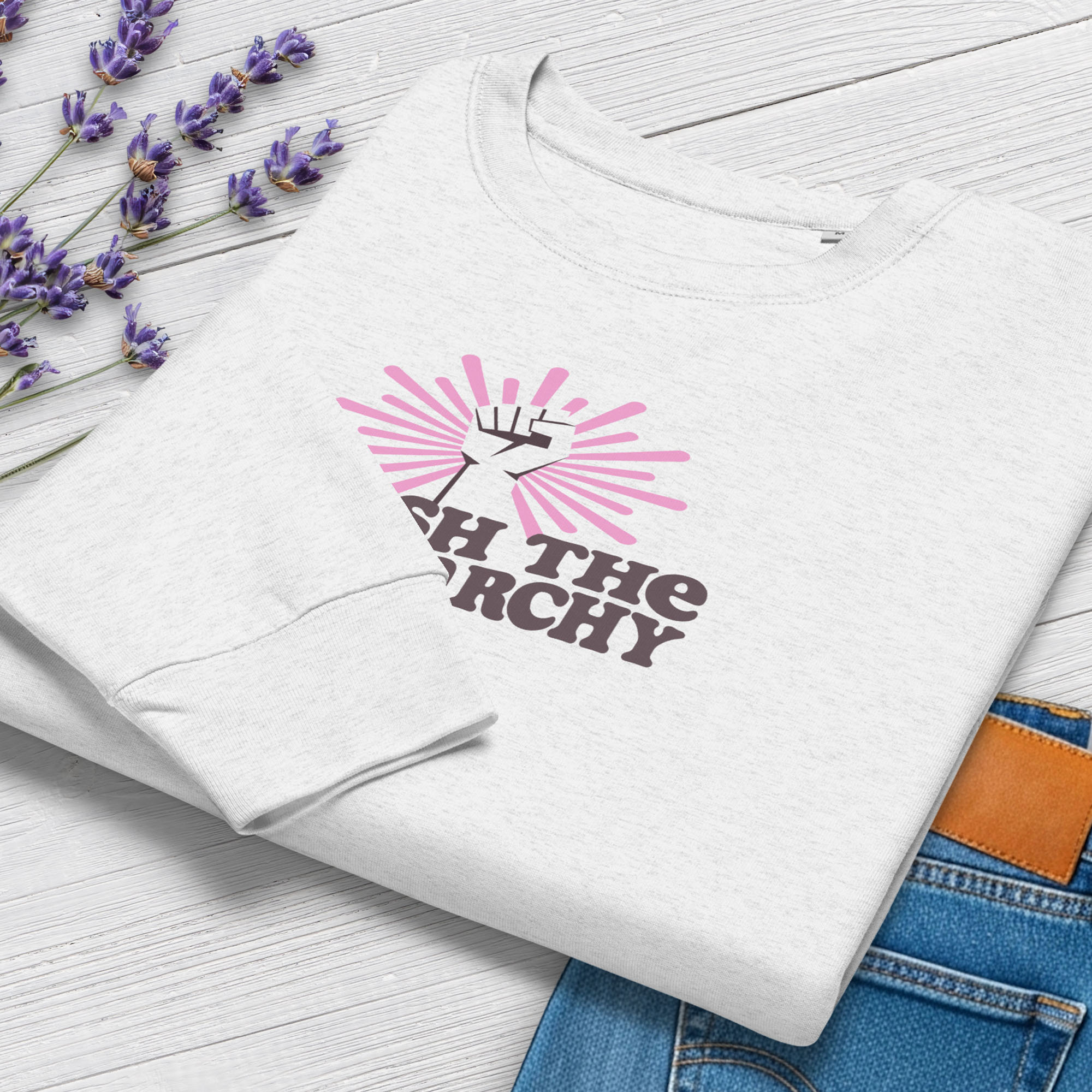 Folded grey sweatshirt to show cuff detail with a raised fist graphic and pink rays behind it, featuring the text “Smash the Patriarchy.”
