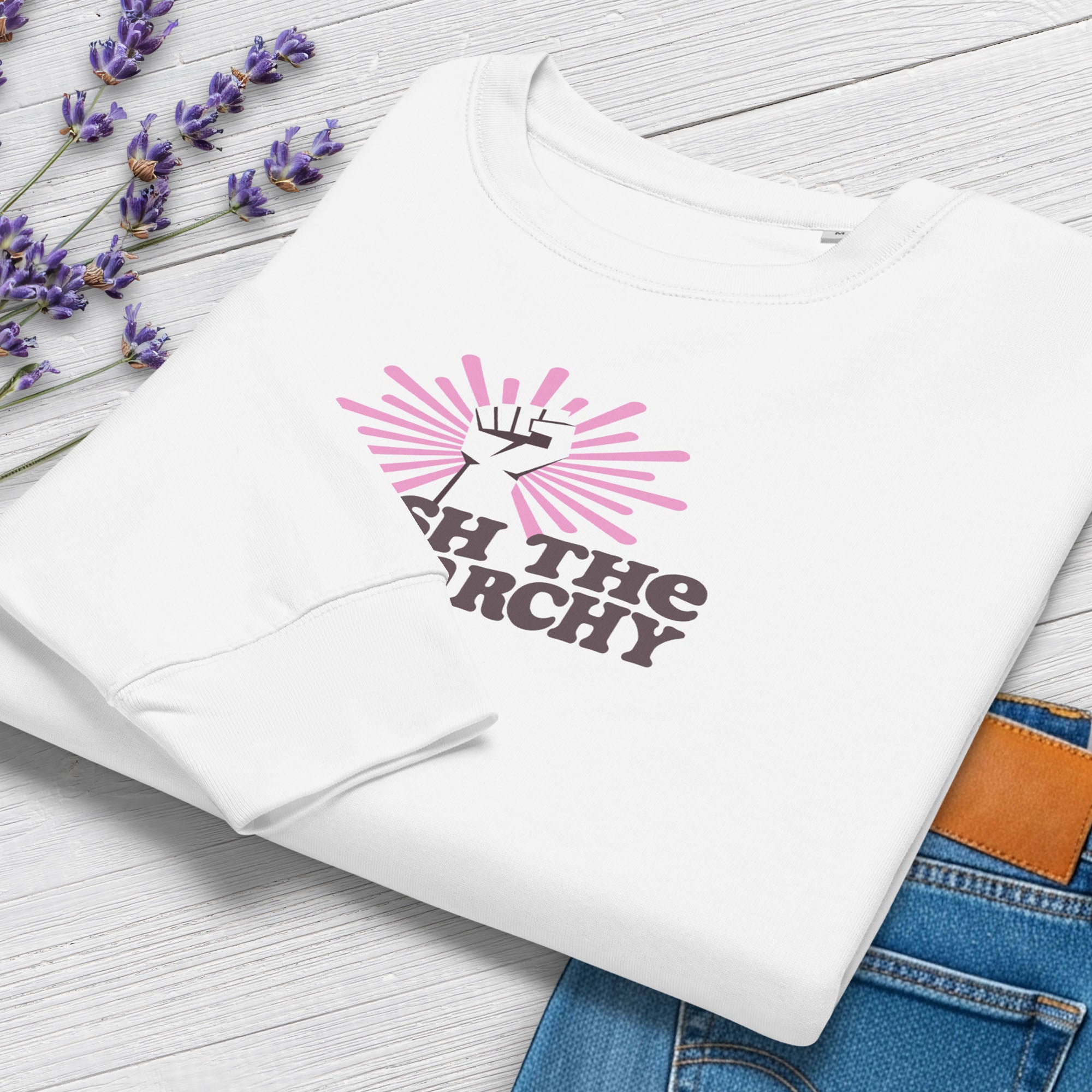 Folded white sweatshirt to show cuff detail with a raised fist graphic and pink rays behind it, featuring the text “Smash the Patriarchy.”