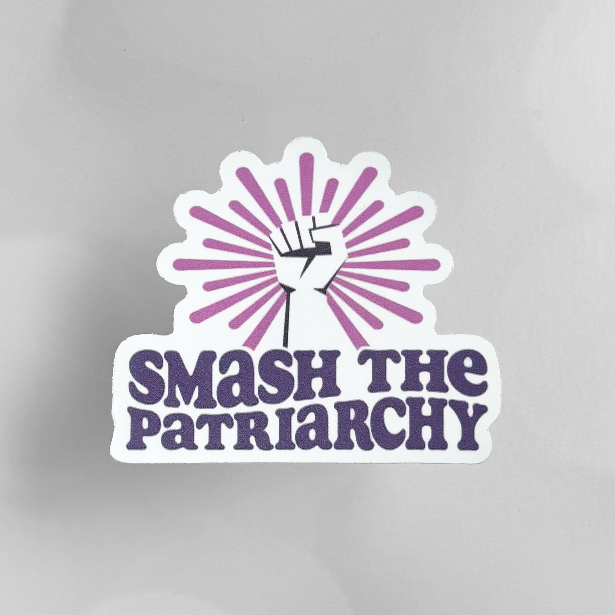 Die-cut vinyl sticker featuring a raised fist with a pink sunburst above the words "Smash the Patriarchy".