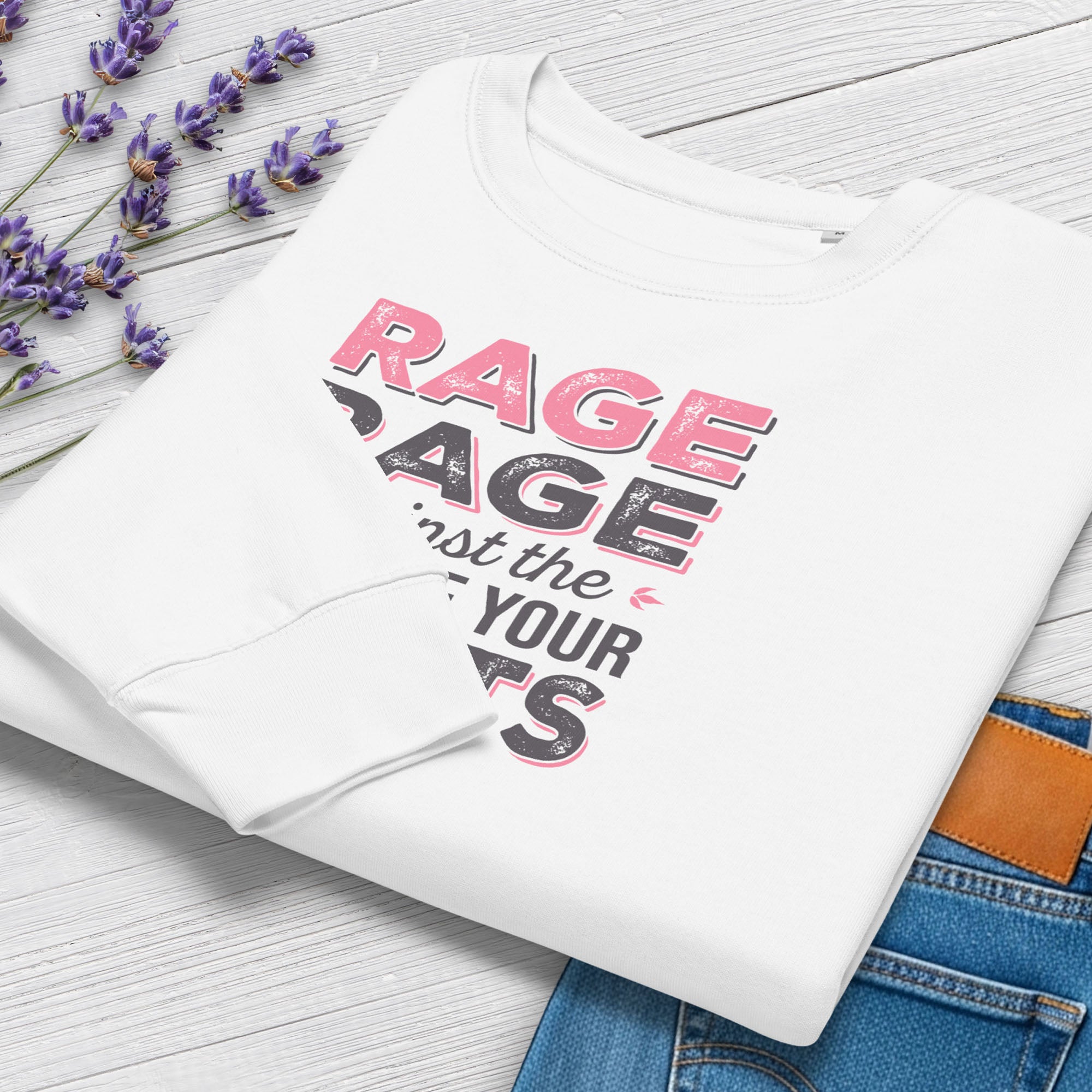 Folded white protest sweatshirt with bold pink and grey text reading “rage rage against the dying of your rights” – feminist anti-trump activist shirt.