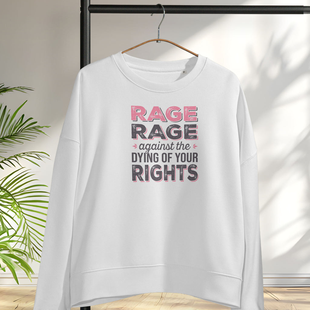 White women's protest sweatshirt with bold pink and grey text reading “rage rage against the dying of your rights” – feminist anti-trump activist shirt, hanging on a hanger.
