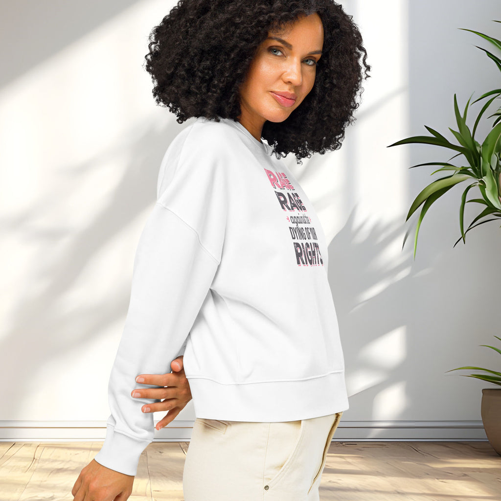 Side view of female model wearing white protest sweatshirt with bold pink and grey text reading “rage rage against the dying of your rights” – feminist anti-trump activist shirt.