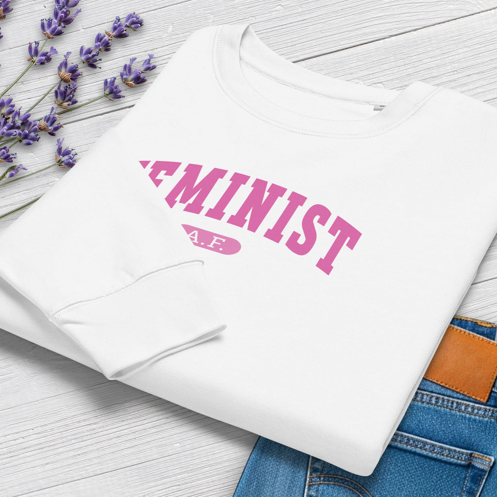Folded white sweatshirt with pink text that reads “Feminist A.F.” in a collegiate style.