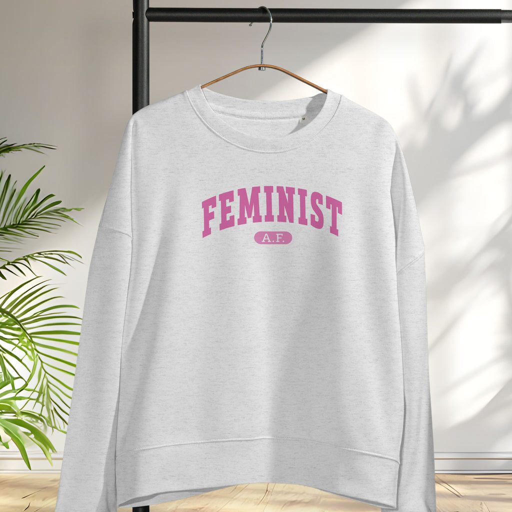 Hanging grey sweatshirt with pink text that reads “Feminist A.F.” in a collegiate style.