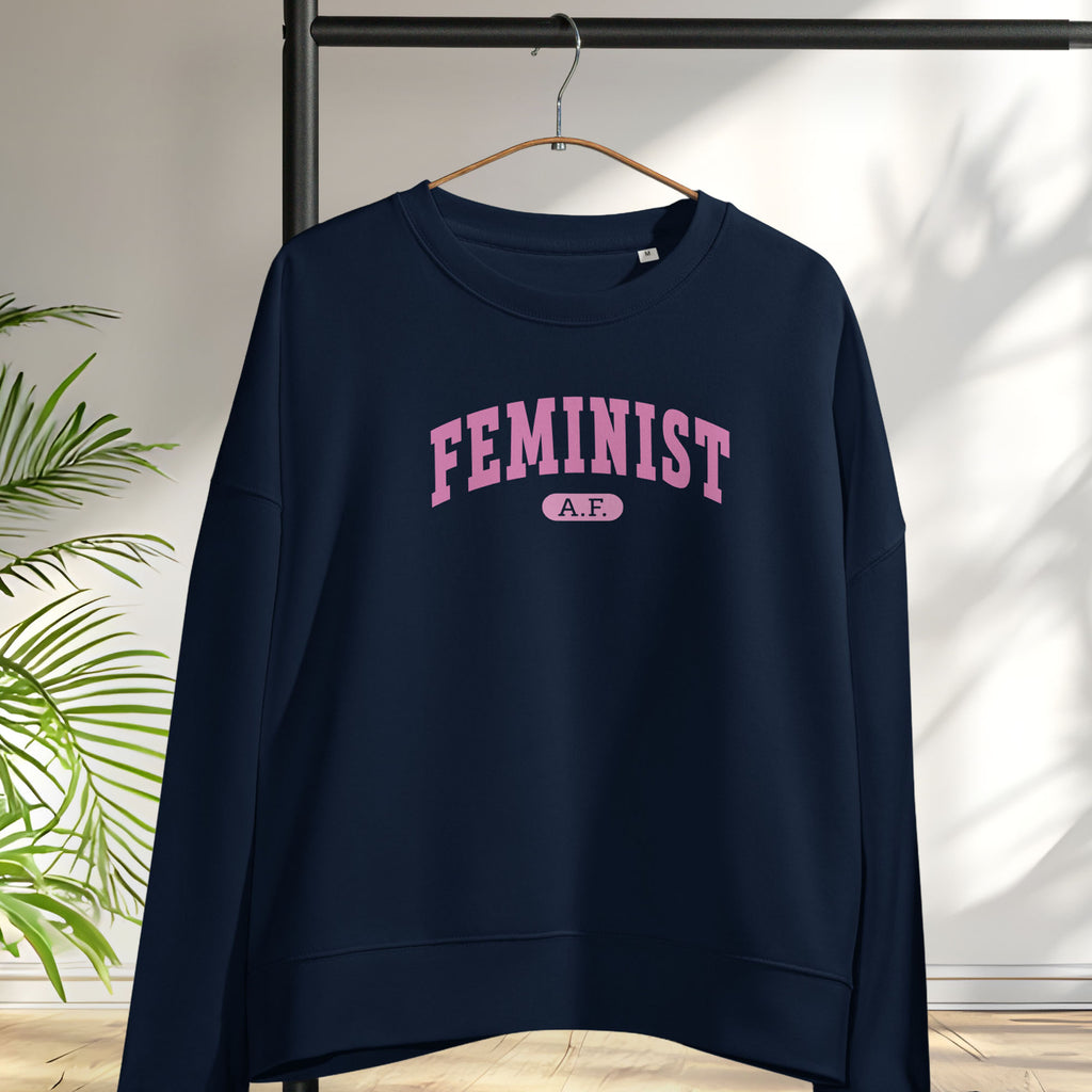 Hanging navy sweatshirt with pink text that reads “Feminist A.F.” in a collegiate style.