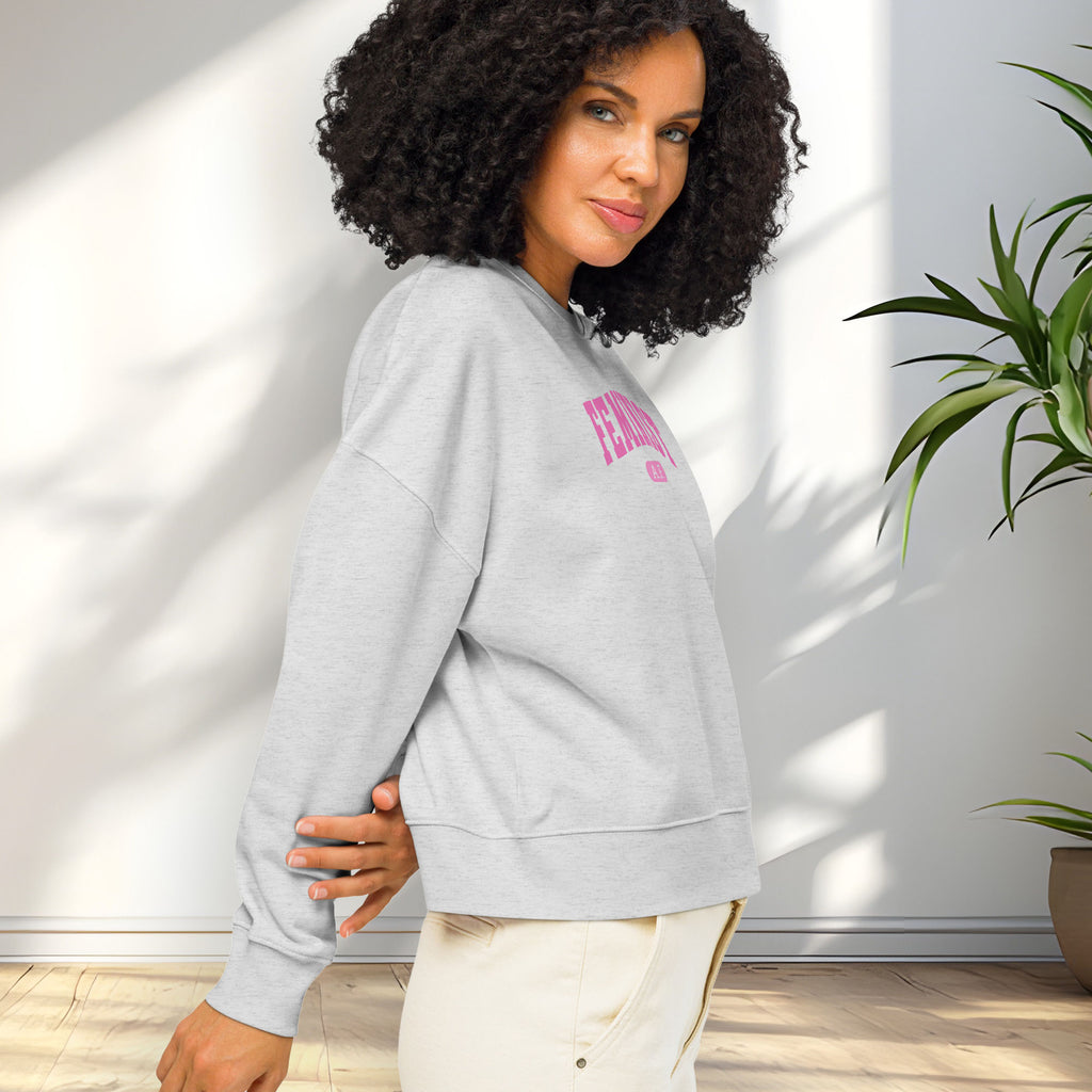 Side view of female model wearing grey sweatshirt with pink text that reads “Feminist A.F.” in a collegiate style.