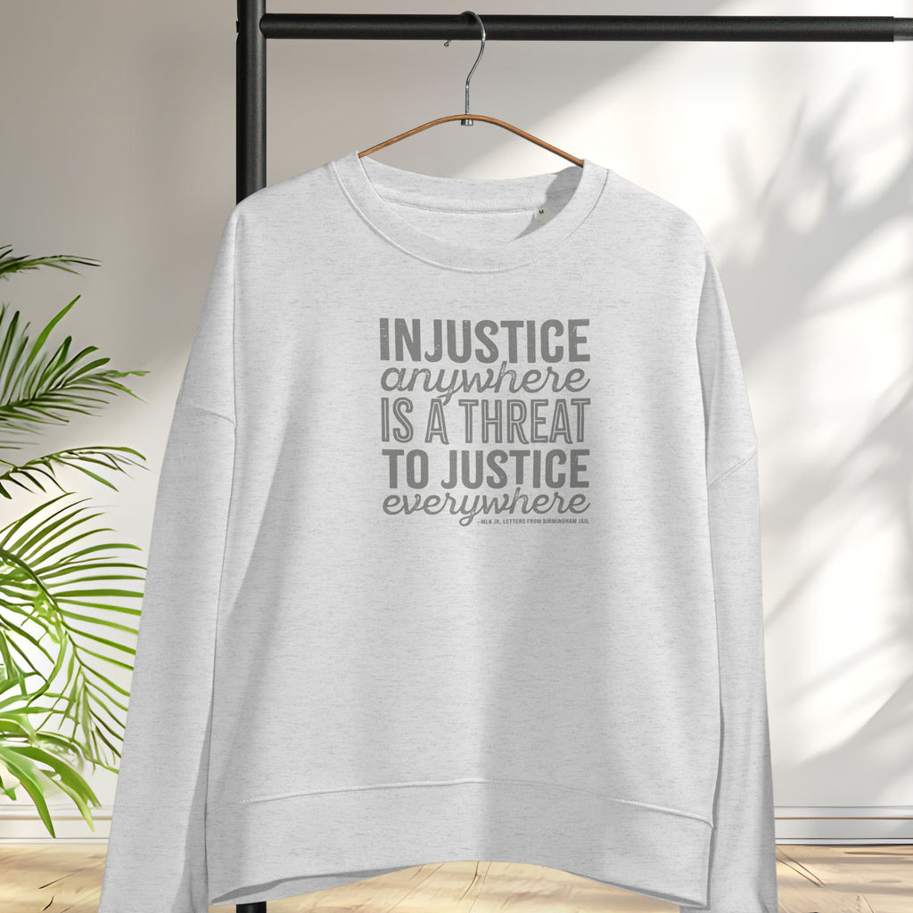 Grey sweatshirt with bold text reading “Injustice anywhere is a threat to justice everywhere” quote from Martin Luther King Jr, MLK Jr, Letters from Birmingham jail — civil rights protest apparel for activists. Hanging on a hanger.